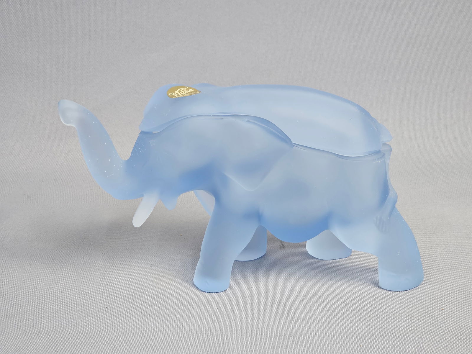 Tiara Exclusives Frosted Satin Glass Elephant Candy Dish: A vintage pressed glass candy dish in the form of a walking elephant, produced by Indiana Glass Company for Tiara Exclusives. The piece is executed in a pale Satin Blue color with a uniform acid-etche