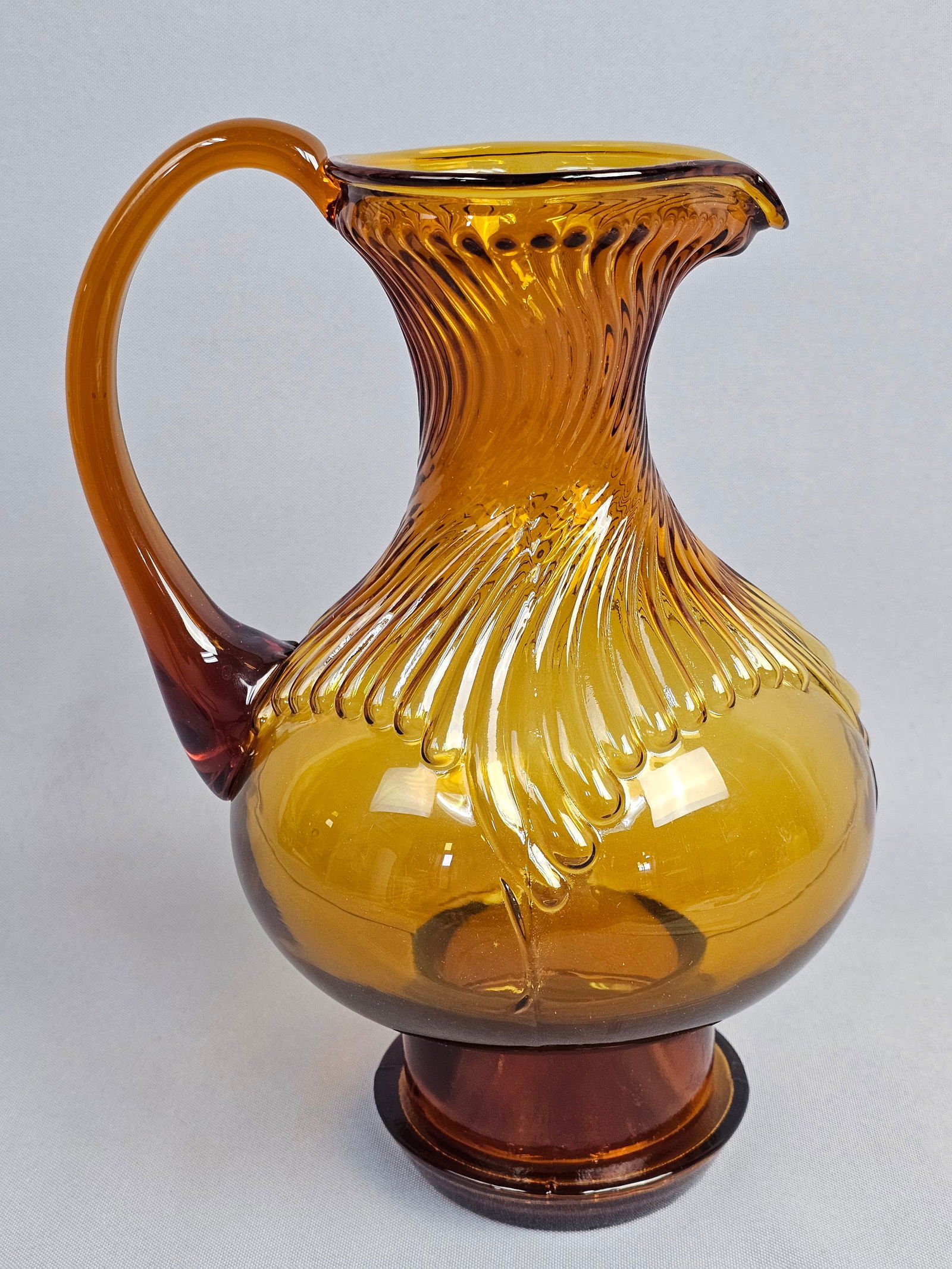 Bohemian Style Optic-Ribbed Amber Art Glass Pitcher: A fine hand-blown art glass pitcher or ewer, likely produced in the late 19th to early 20th century. The vessel is executed in a rich honey-amber glass that transitions to a deeper burnt-sienna at the