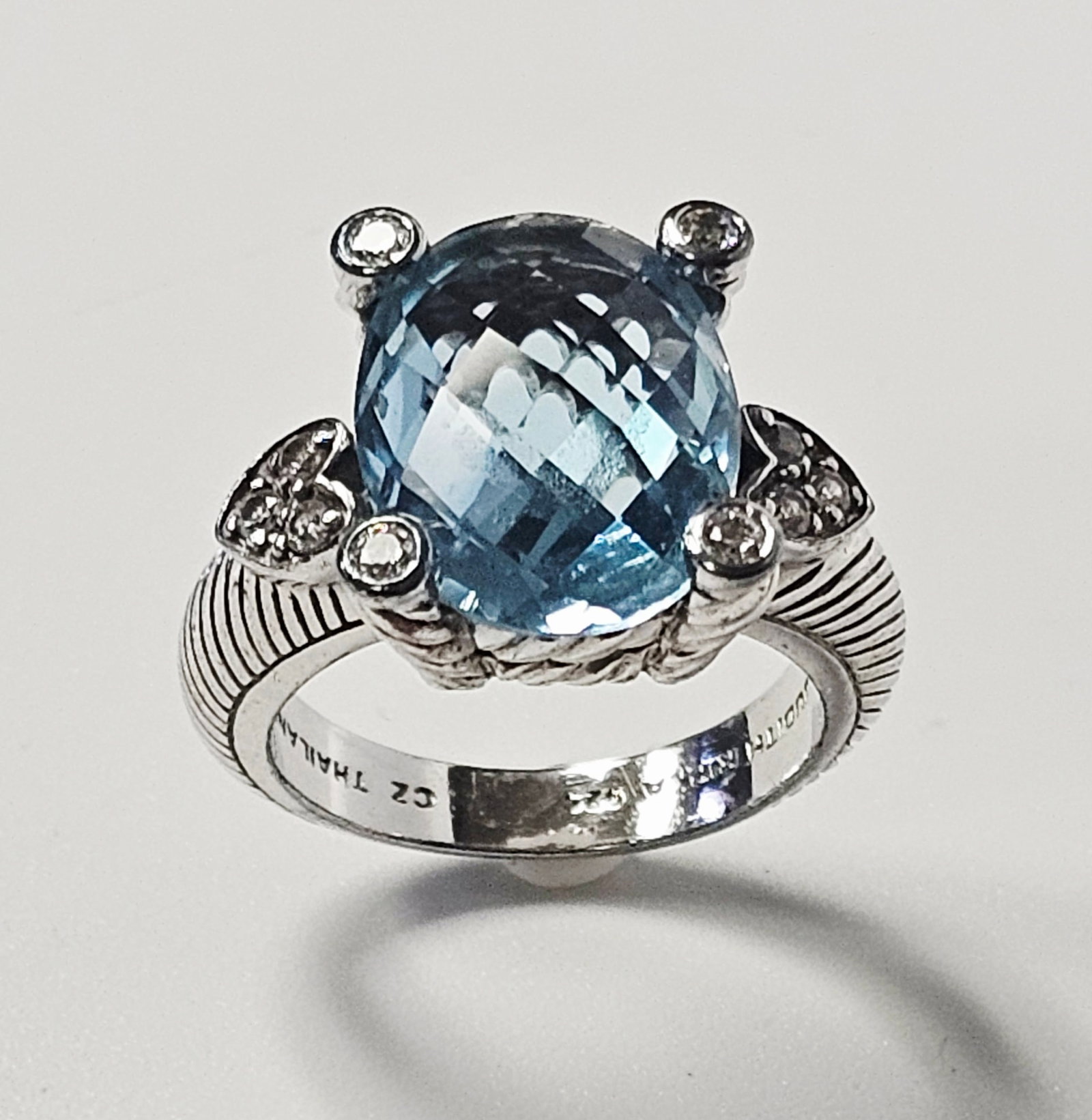 Judith Ripka Sterling Cubic Zirconia Ring 8.0 Grams: A sterling silver cocktail ring by designer Judith Ripka. The ring features a central large oval-cut light blue stone with a checkerboard-faceted crown. The center stone is secured in a four-prong set