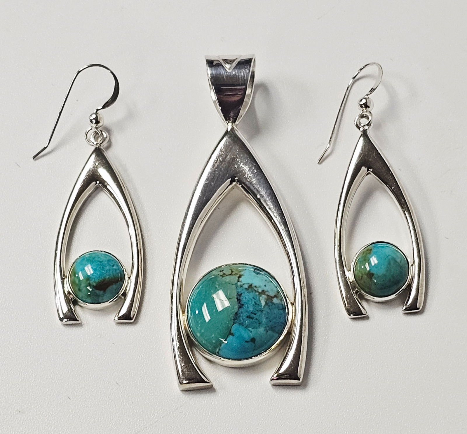 Sterling Turquoise Earrings & Pendant 18.0 Grams: This jewelry set consists of a pendant and a matched pair of drop earrings. Each piece is crafted from silver. A round turquoise cabochon with a natural matrix is bezel-set within the center of each o