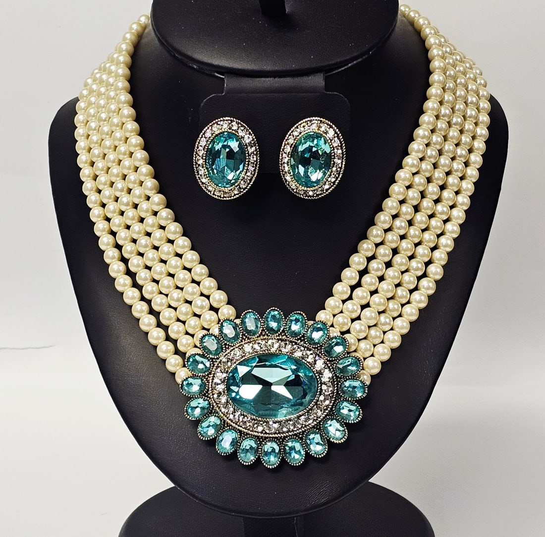 Heidi Daus Faux Pearl and Aquamarine-Toned Crystal Necklace and Earring Set: This two-piece costume jewelry set by designer Heidi Daus consists of a multi-strand statement necklace and coordinating earrings. The necklace features five graduated strands of cream-colored faux pe