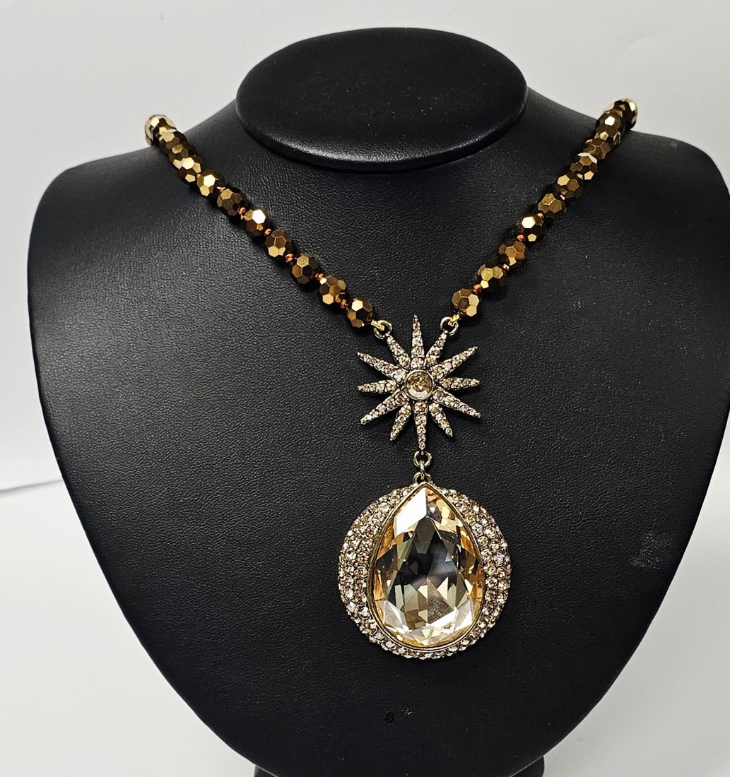 Heidi Daus Star and Pear Pendant Beaded Necklace: A gold-tone necklace featuring champagne-colored faceted beads and a crystal-set star and pear-shaped pendant, measuring up to 24 inches in length.