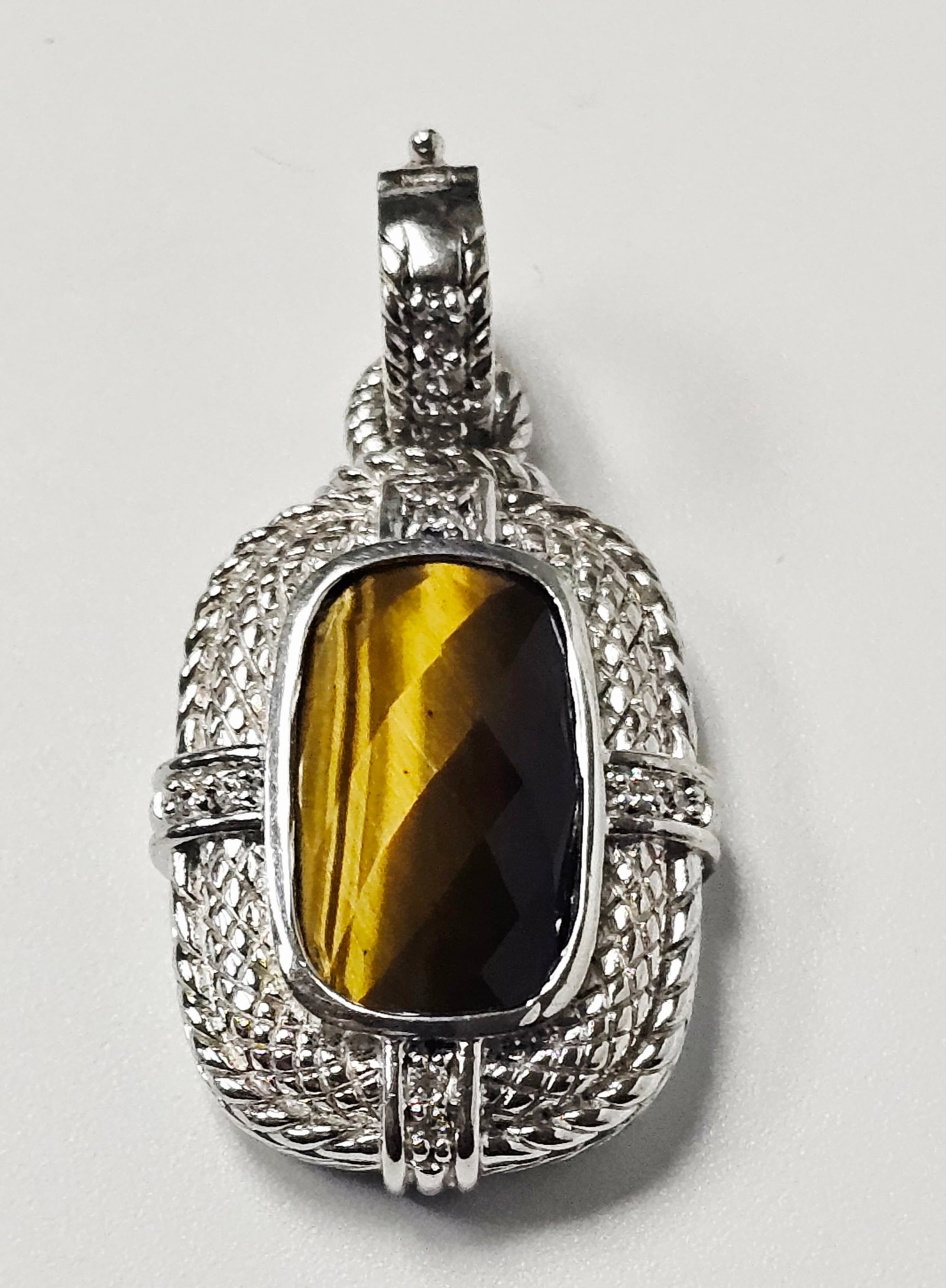 Judith Ripka Sterling Tiger's Eye Pendant 11.8 Grams: A sterling silver pendant by Judith Ripka featuring a central rectangular faceted tiger's eye gemstone. The gemstone is mounted in a frame with textured basket-weave and cable-style detailing. Small,