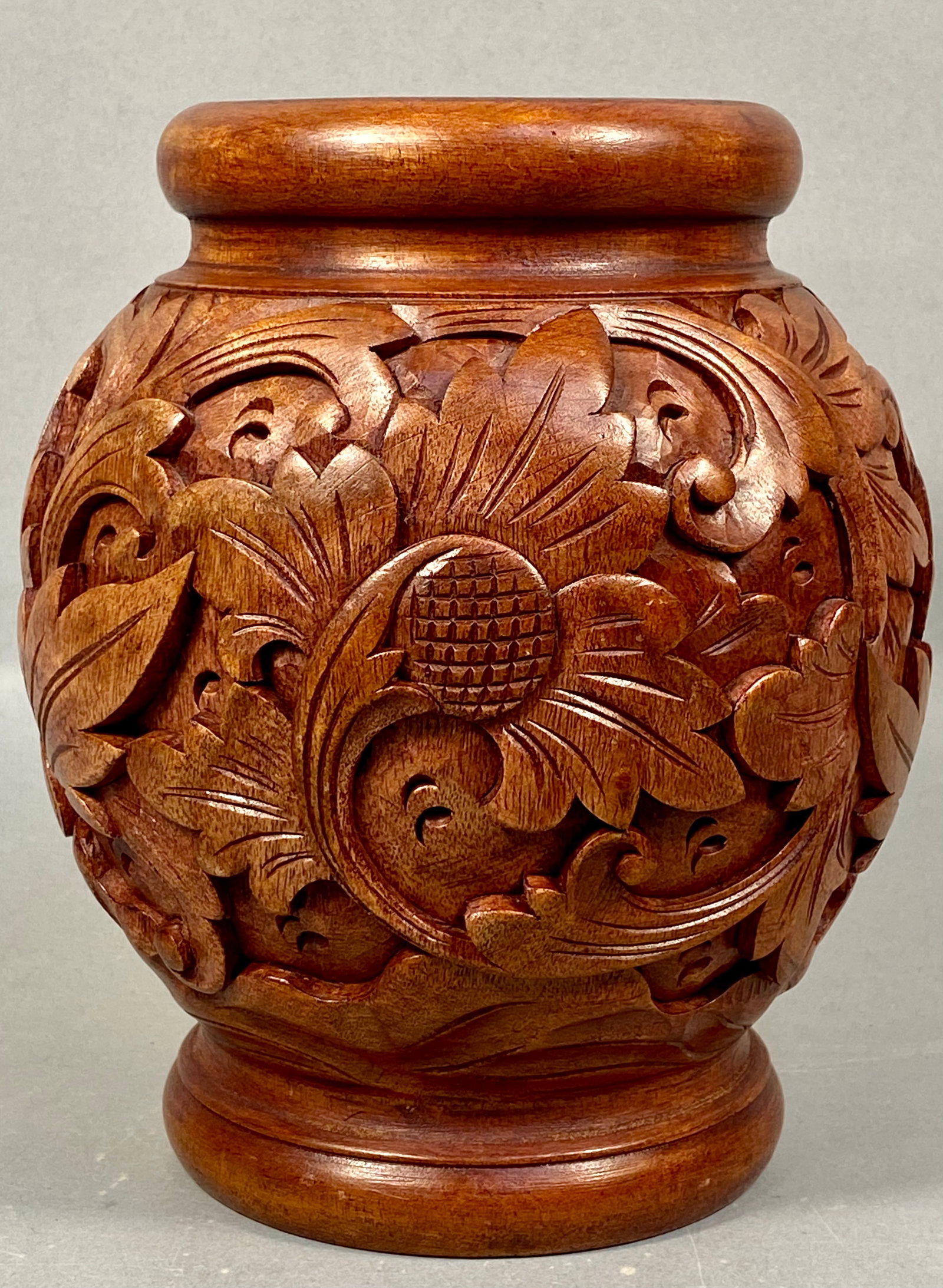 Hand-Carved Wooden Vase with Botanical Relief Decoration: A hand-carved wooden vase of globular form featuring a thick rolled rim and a stepped flared foot. The body is decorated with high-relief carvings of scrolling acanthus-style foliage and various botan