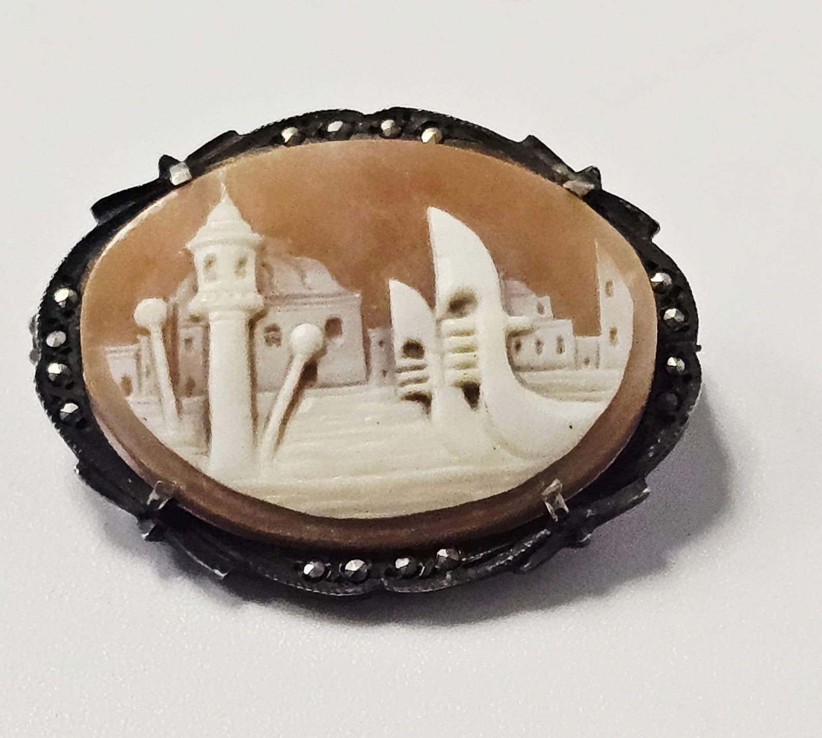 Sterling Venetian Architectural Scene Carved Shell Cameo Brooch: An oval carved shell cameo featuring a relief depiction of a Venetian architectural scene. The foreground shows a gondola on water, while the background includes buildings and a campanile tower. The s