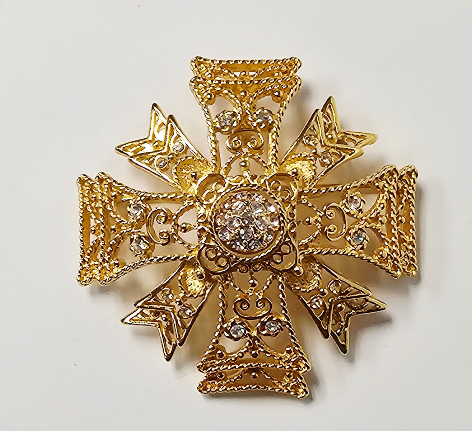Kenneth Jay Lane Reversible Rhinestone Maltese Cross Brooch: A Kenneth Jay Lane (KJL) ornate costume jewelry brooch designed in the form of a stylized Maltese cross or cross pattee. The piece is constructed from gold-toned base metal with an openwork filigree d