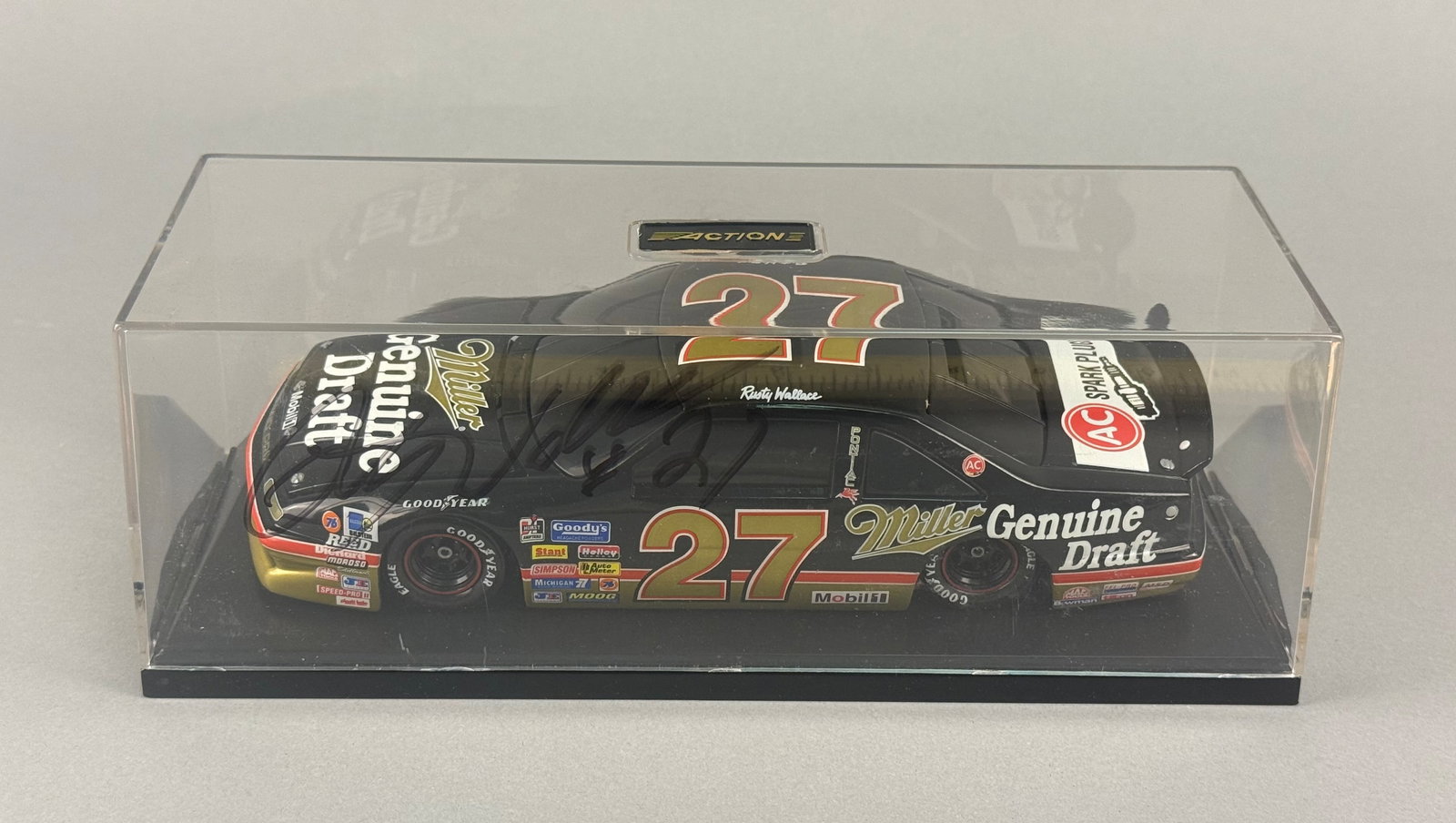 Action Performance Rusty Wallace No. 27 Miller Genuine Draft Pontiac NASCAR Die-Cast Model: Action Performance die-cast model of Rusty Wallace's No. 27 Miller Genuine Draft Pontiac Grand Prix NASCAR stock car. The model features the black, gold, and red livery associated with the 1990 racing