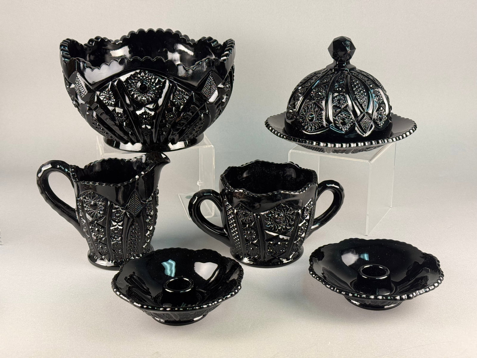 A Collection of Tiara Exclusives Monarch Pattern Black Amethyst Pressed Glass Tableware: This collection of opaque black pressed glass tableware is attributed to Tiara Exclusives in the Monarch pattern, manufactured by Indiana Glass circa 1970-1980. The assortment includes a large bowl wi