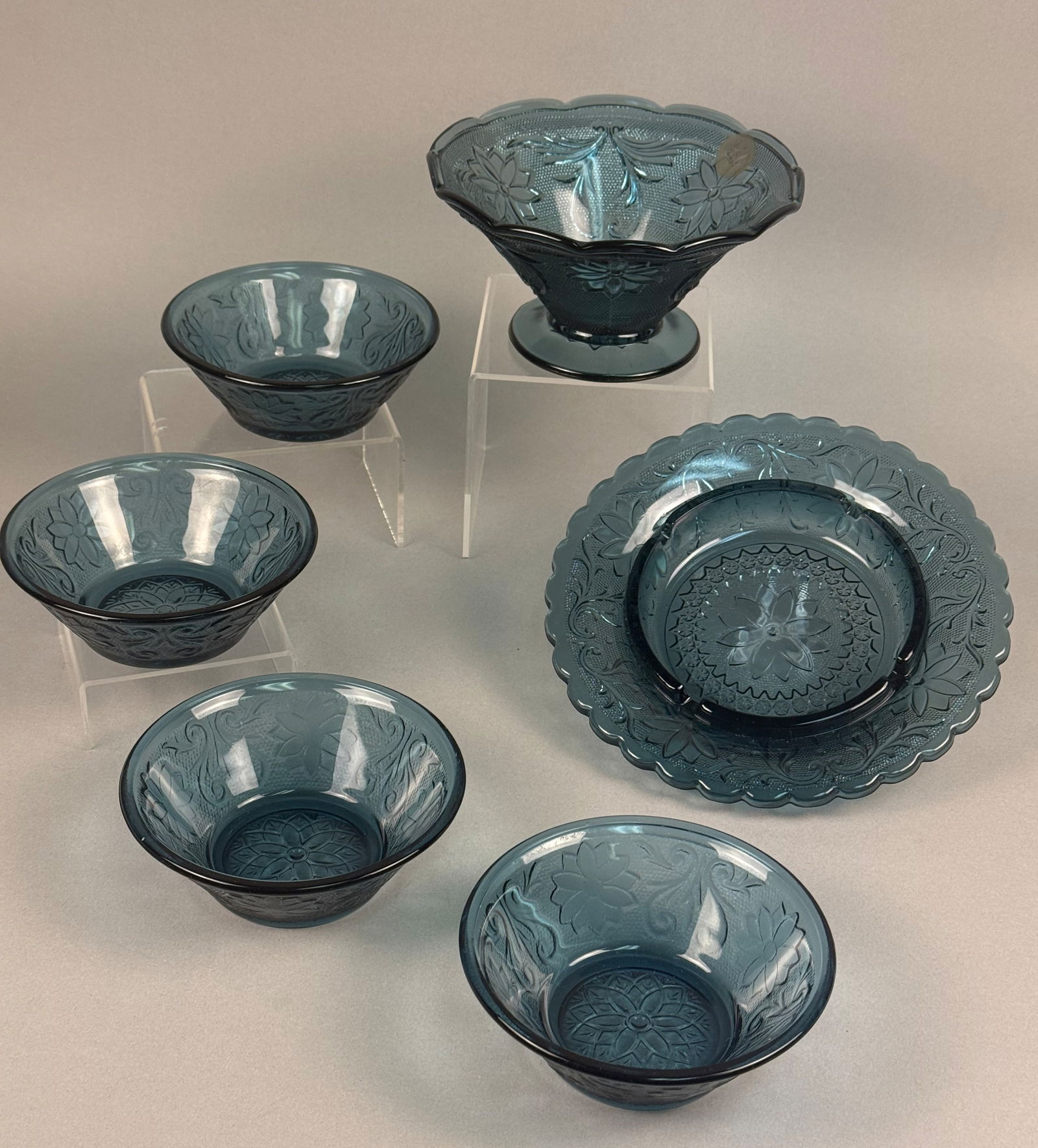 A Set of Seven Pieces of Tiara Exclusives Sandwich Pattern Spruce Blue Glassware: This set of seven pieces of pressed glassware is manufactured in the Sandwich pattern, a design produced by the Indiana Glass Company for distribution through Tiara Exclusives starting in the 1970s. T