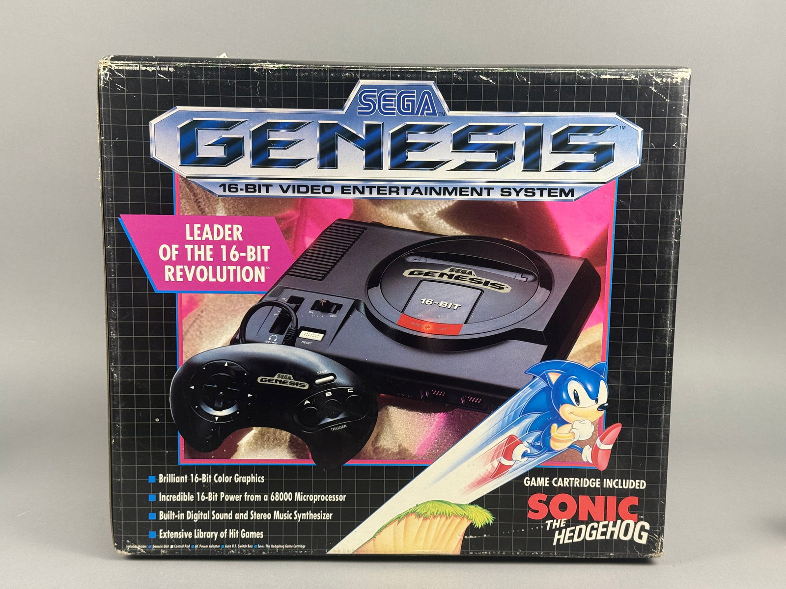Sega Genesis 16-Bit Video Entertainment System Original Box and Packaging: This lot comprises the original retail packaging and select internal components for a Sega Genesis 16-Bit Video Entertainment System, specifically the Sonic the Hedgehog bundle. The item is housed in