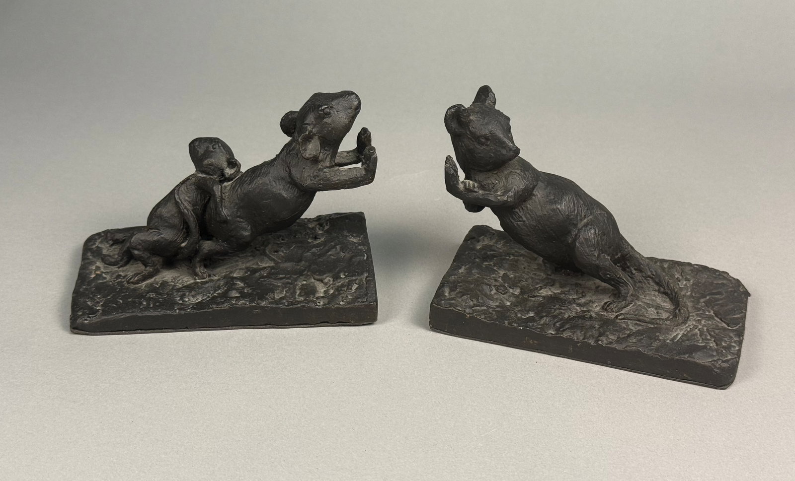 A Pair of Contemporary Cast Metal Rodent Bookends: This pair of contemporary cast metal sculptures depicts rodents in expressive, upright poses. The figures are rendered in a gestural, heavily modeled style with a dark brown to black matte patina. One