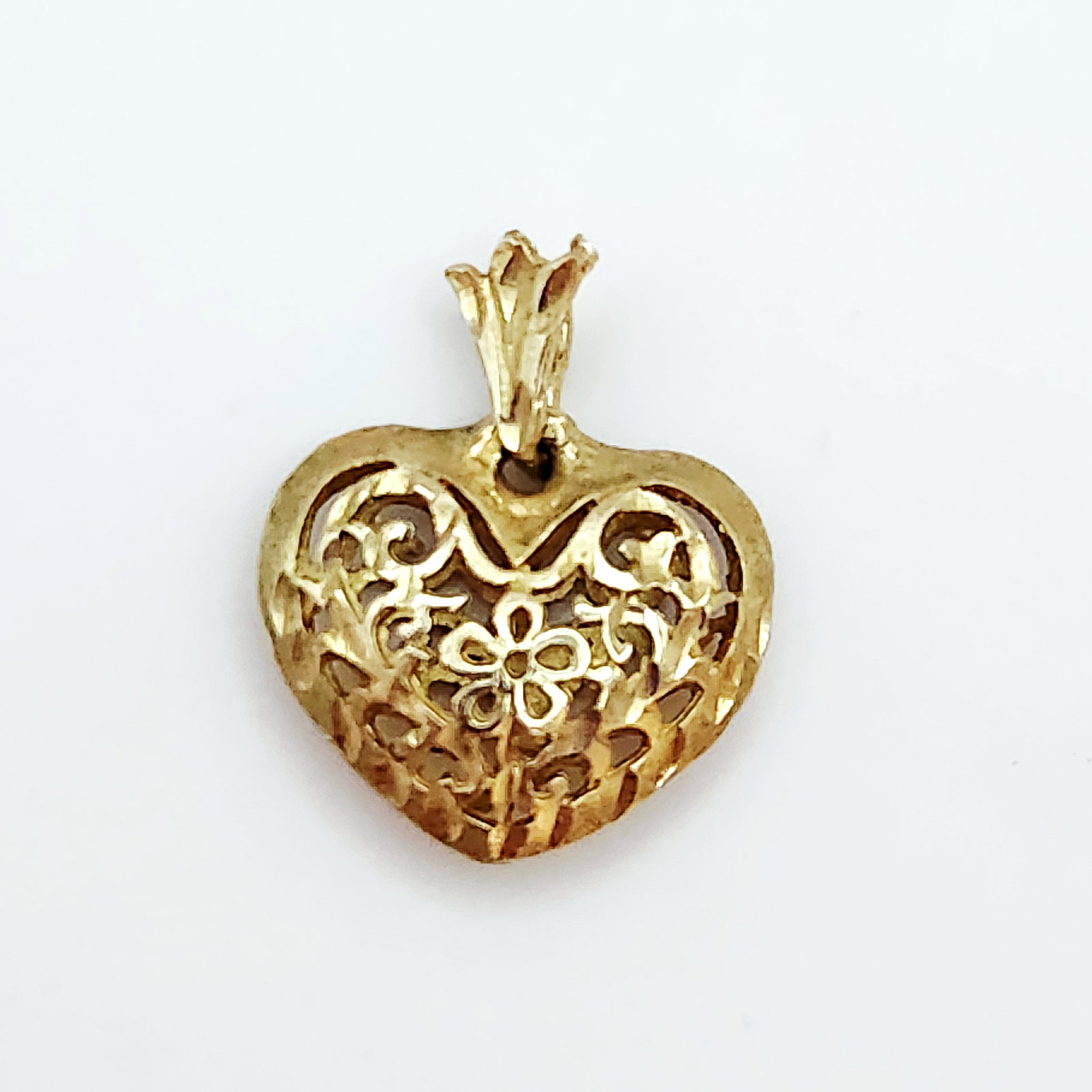 10K Gold Filigree Heart Pendant 2.6 Grams: This item is crafted in 10 karat yellow gold and features a hollow, puffed heart pendant. The heart is decorated with an intricate openwork filigree design centered around a stylized four-petal flower