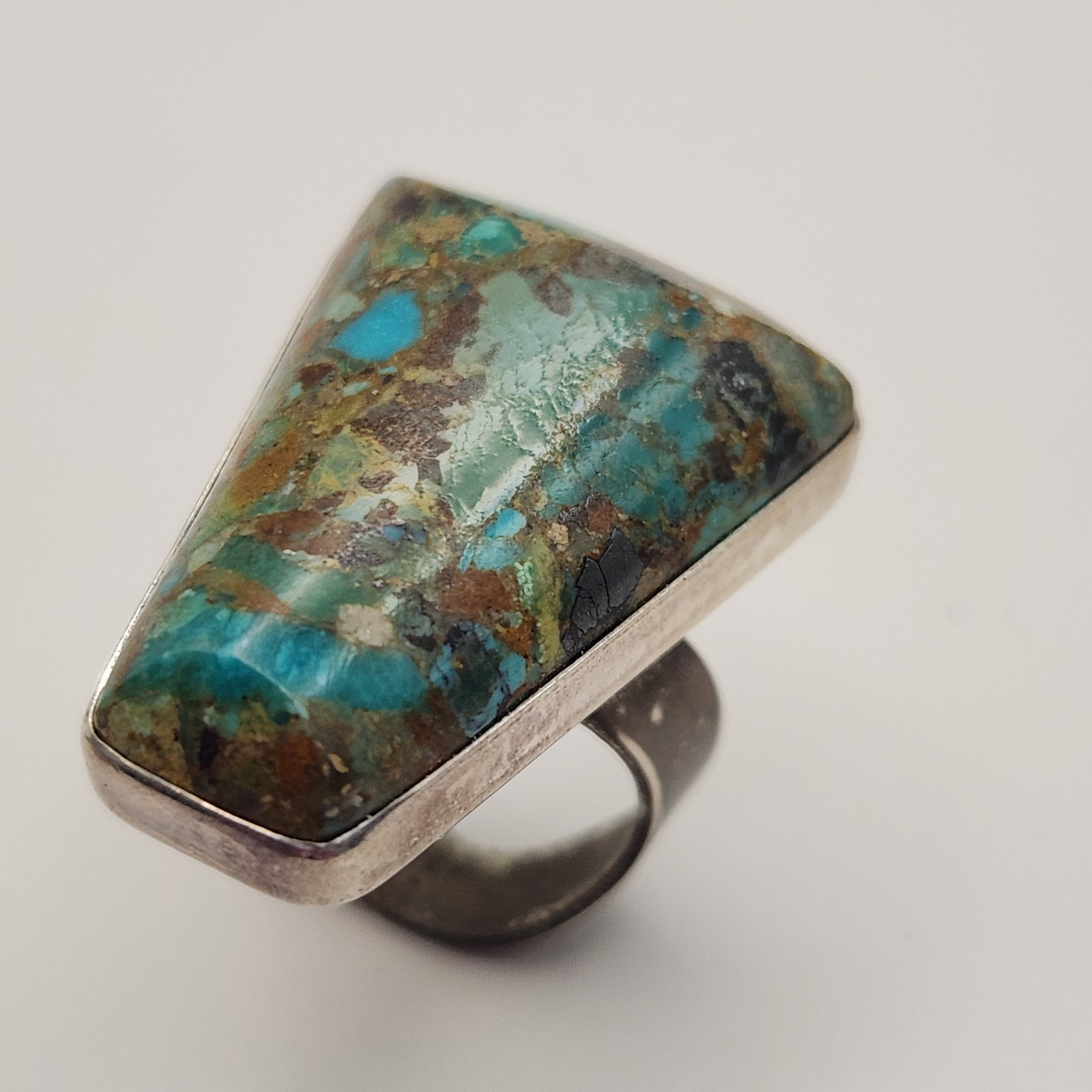 Sterling Turquoise Ring 11.0 Grams: A sterling silver ring featuring a large trapezoidal blue, green, and brown turquoise stone, weighing 11.0 grams and measuring approximately size 6. Good vintage condition.