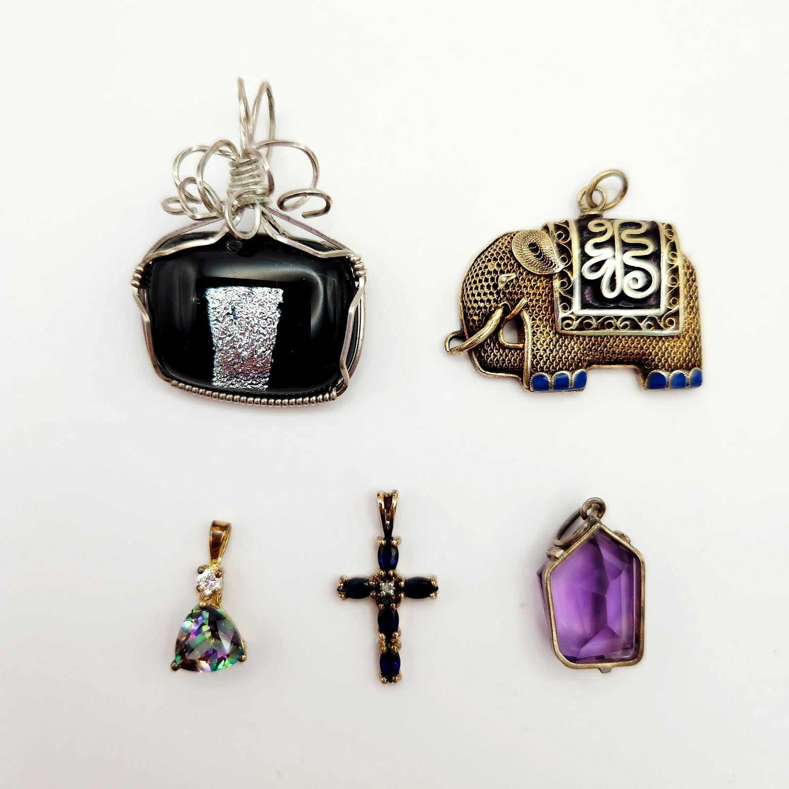 Assorted Pendants Including Sterling 10.8 Grams: A collection of jewelry pendants in various styles and materials. Included is a filigree-style elephant pendant featuring blue enamel accents and intricate scrollwork. Also present is a large rectangu