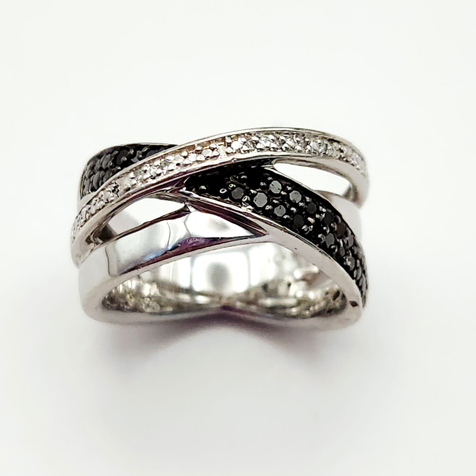 Sterling CZ Crossover Ring 8.3 Grams: A sterling silver crossover-style ring featuring pave-set bands of black and white stones, weighing 8.3 grams and measuring approximately size 7. Very good vintage condition.