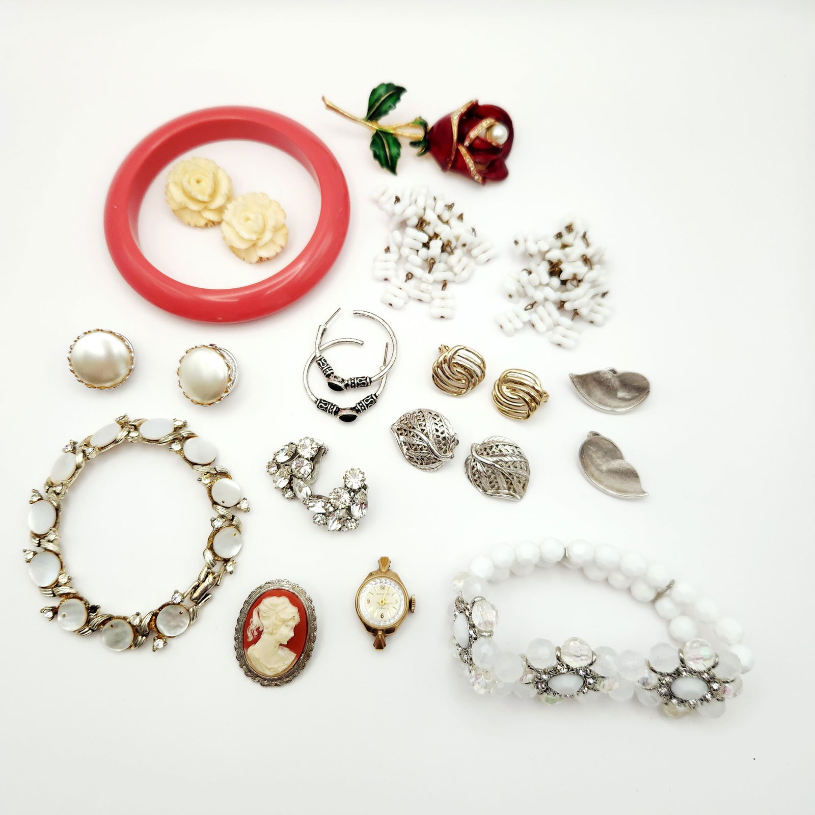 An Assortment of Vintage Costume Jewelry and Westclox Watch Head Including Weiss, Monet, and Puccini: This collection of vintage costume jewelry features several signed pieces and a manual wind watch head. The lot includes a pair of Weiss clip-on earrings featuring marquise and round-cut clear rhinest