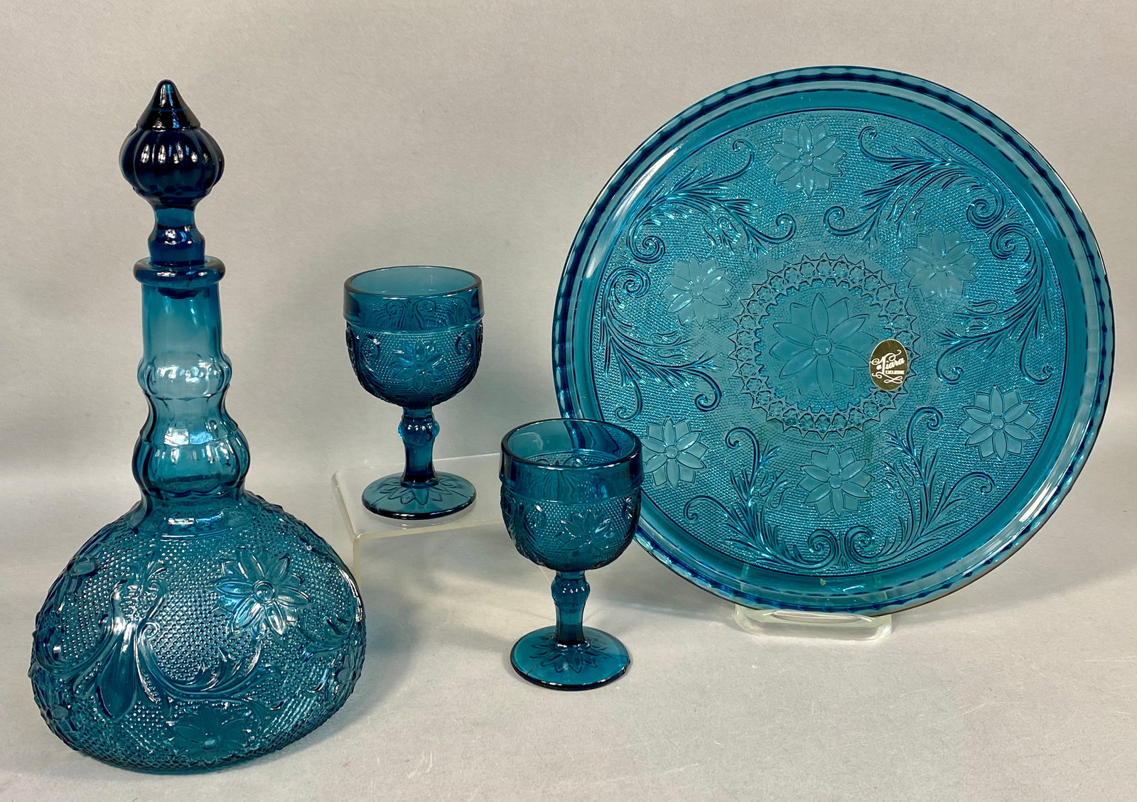 Tiara Exclusives Bicentennial Wine Set, circa 1976: Tiara Exclusives wine service set in the Sandwich pattern, manufactured by the Indiana Glass Company. This set is finished in a teal Colonial Blue colorway and was produced to commemorate the United S