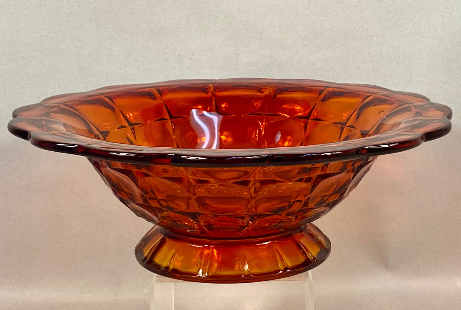 Vintage Amber Pressed Glass Moon and Stars Pattern Pedestal Bowl: This vintage footed bowl is crafted from transparent amber-toned pressed glass featuring the Moon and Stars pattern, a design characterized by circular depressions and starburst motifs. The piece is s