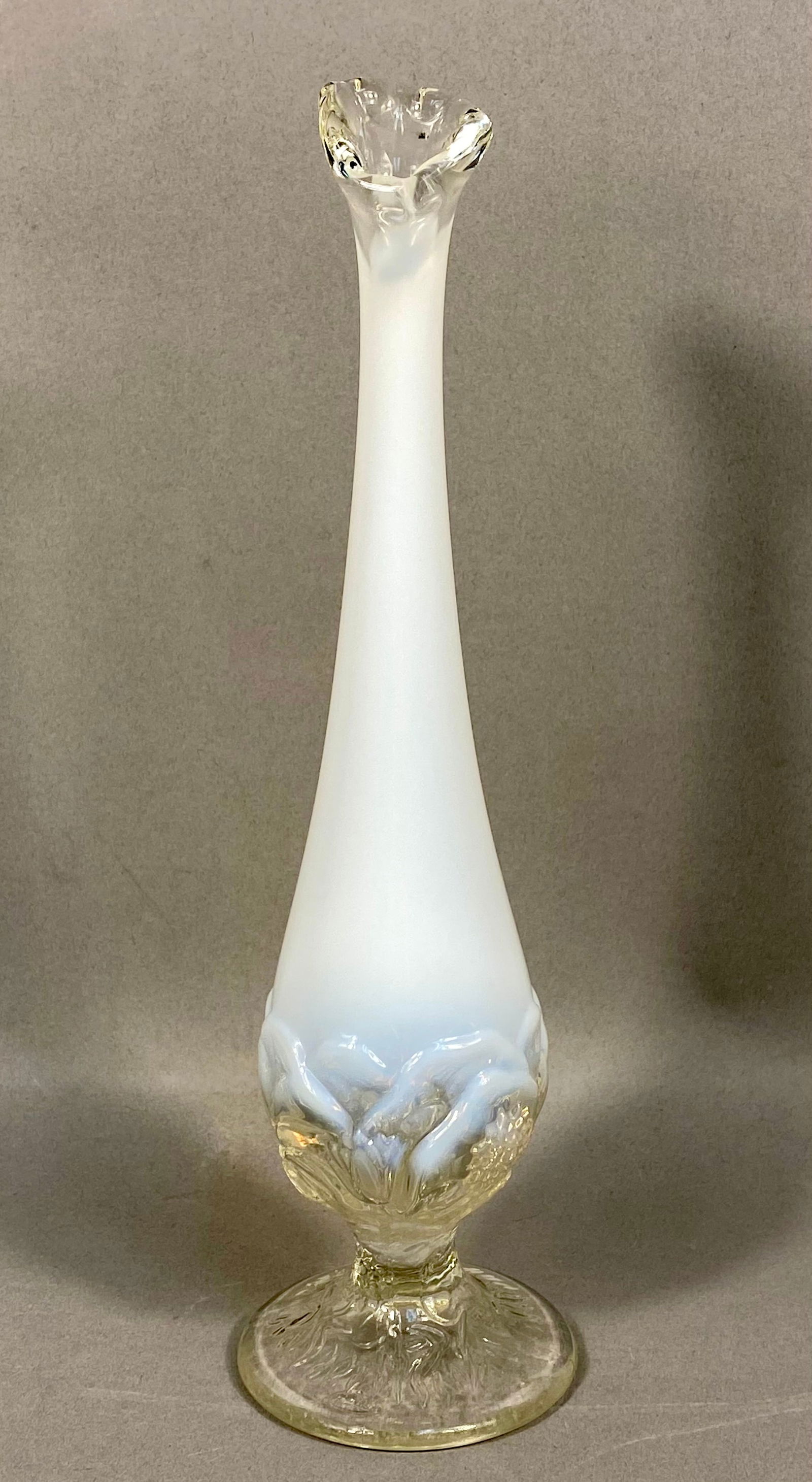 Fenton Art Glass Opalescent Rose Bud Vase: A vintage bud vase by Fenton Art Glass featuring a slender, tapered neck and a ruffled, flared rim. The bulbous lower section is decorated with a molded rose and foliage pattern. The piece is executed