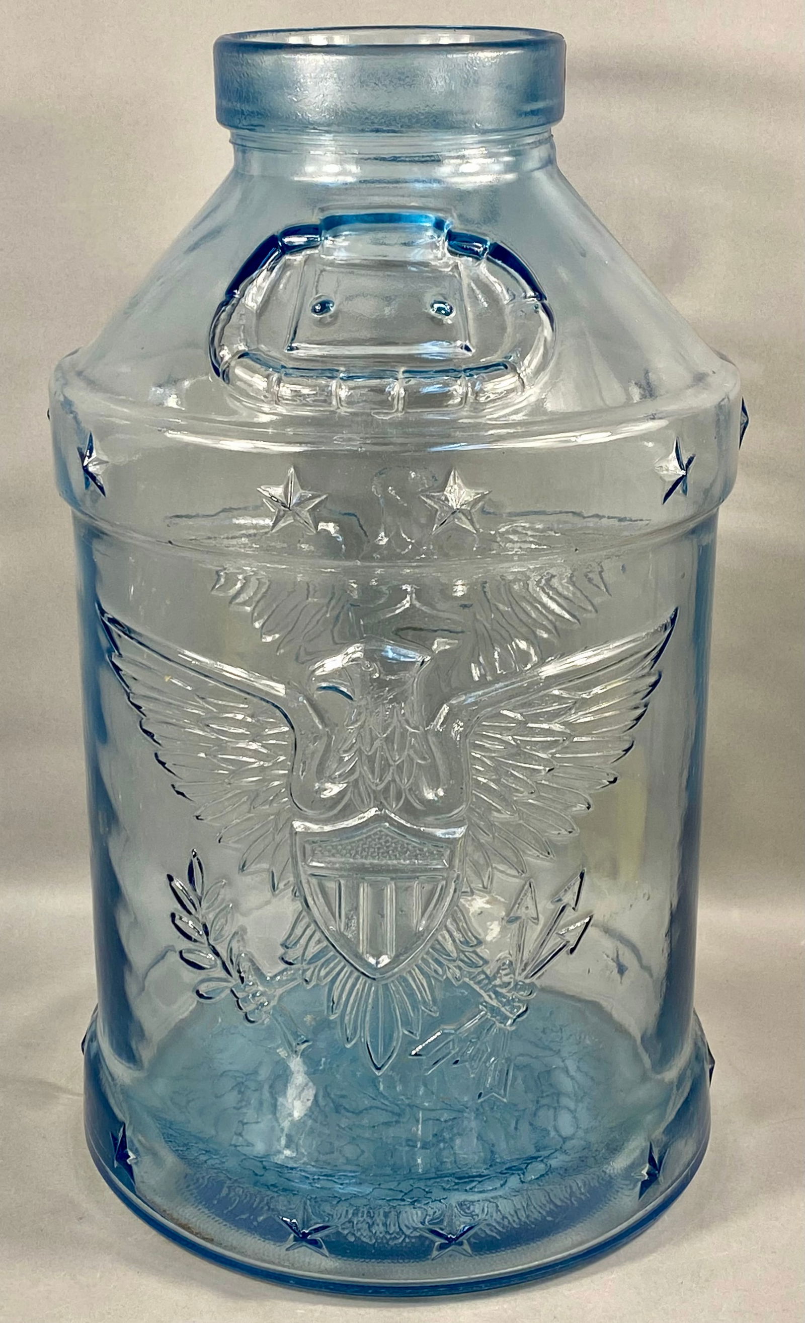 Large 5 Gallon Blue Molded Glass Bicentennial Eagle Jar: A large five gallon capacity molded glass jar in a light blue tint, identified as a Bicentennial commemorative piece produced by Libbey Glass Company. The vessel features a cylindrical body with slope