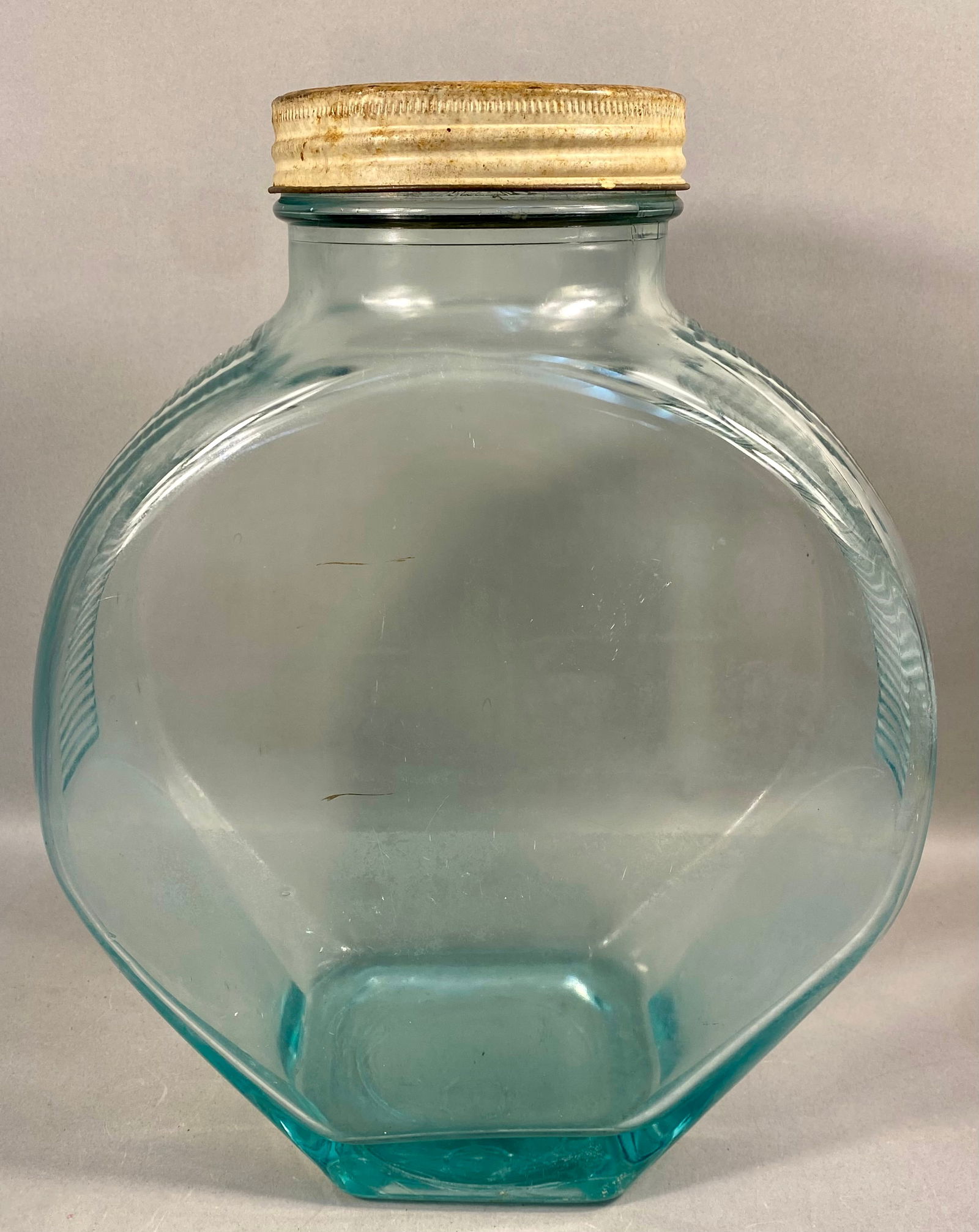 Large Aqua Glass Ribbed Display Jar with Metal Lid: This aqua-blue glass storage or display jar features a circular, flat-sided body with vertical ribbing on the narrow sides. The piece is constructed of pressed glass and includes a short neck with a t
