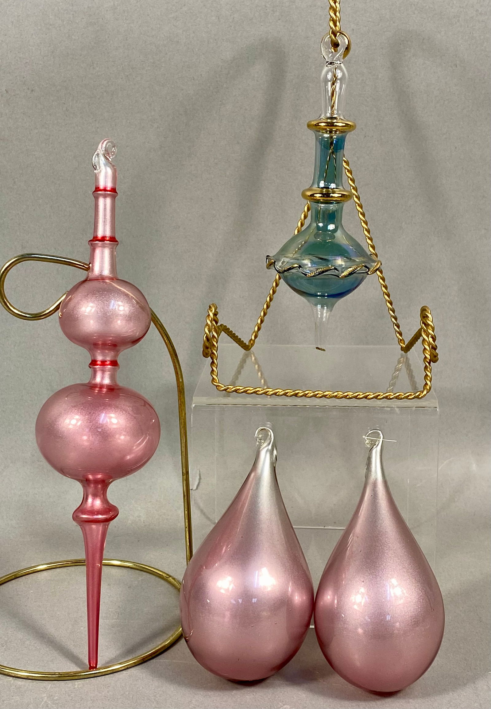 A Group of Four Hand-Blown Glass Ornaments: This collection consists of four hand-blown glass ornaments in two distinct styles. The first group includes three ornaments featuring a pearlescent pink satin finish. This group is comprised of one l