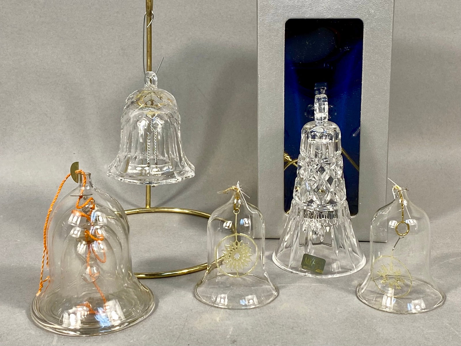 A Collection of Five Crystal and Glass Bell Ornaments Including Mikasa: This collection consists of five glass and crystal bell ornaments. The group features a Mikasa Colonial pattern crystal bell ornament manufactured in Germany, characterized by geometric and faceted cu