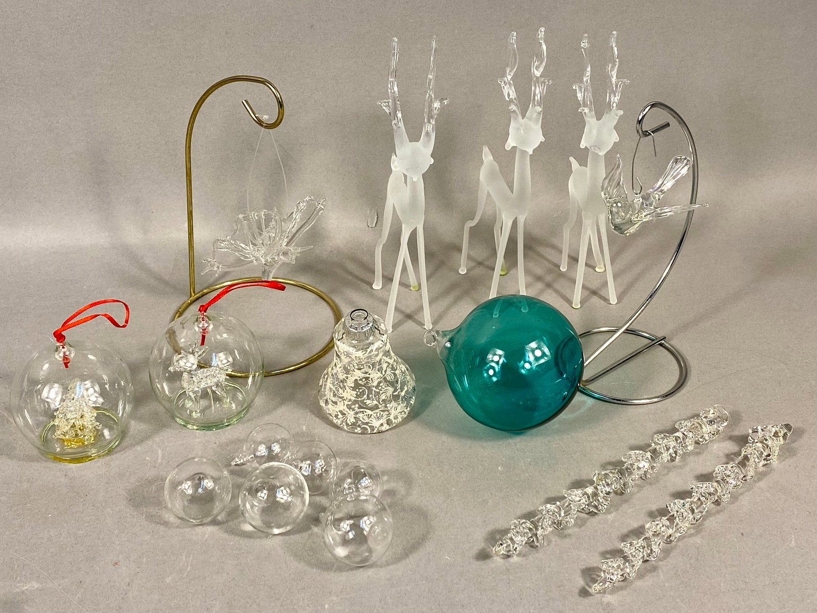 A Collection of Glass Holiday Ornaments and Figurines Including West German Bell and Attributed: A collection of decorative glass holiday ornaments and figurines of various styles and origins. The lot includes three stylized reindeer figurines featuring frosted glass bodies and clear glass multi-