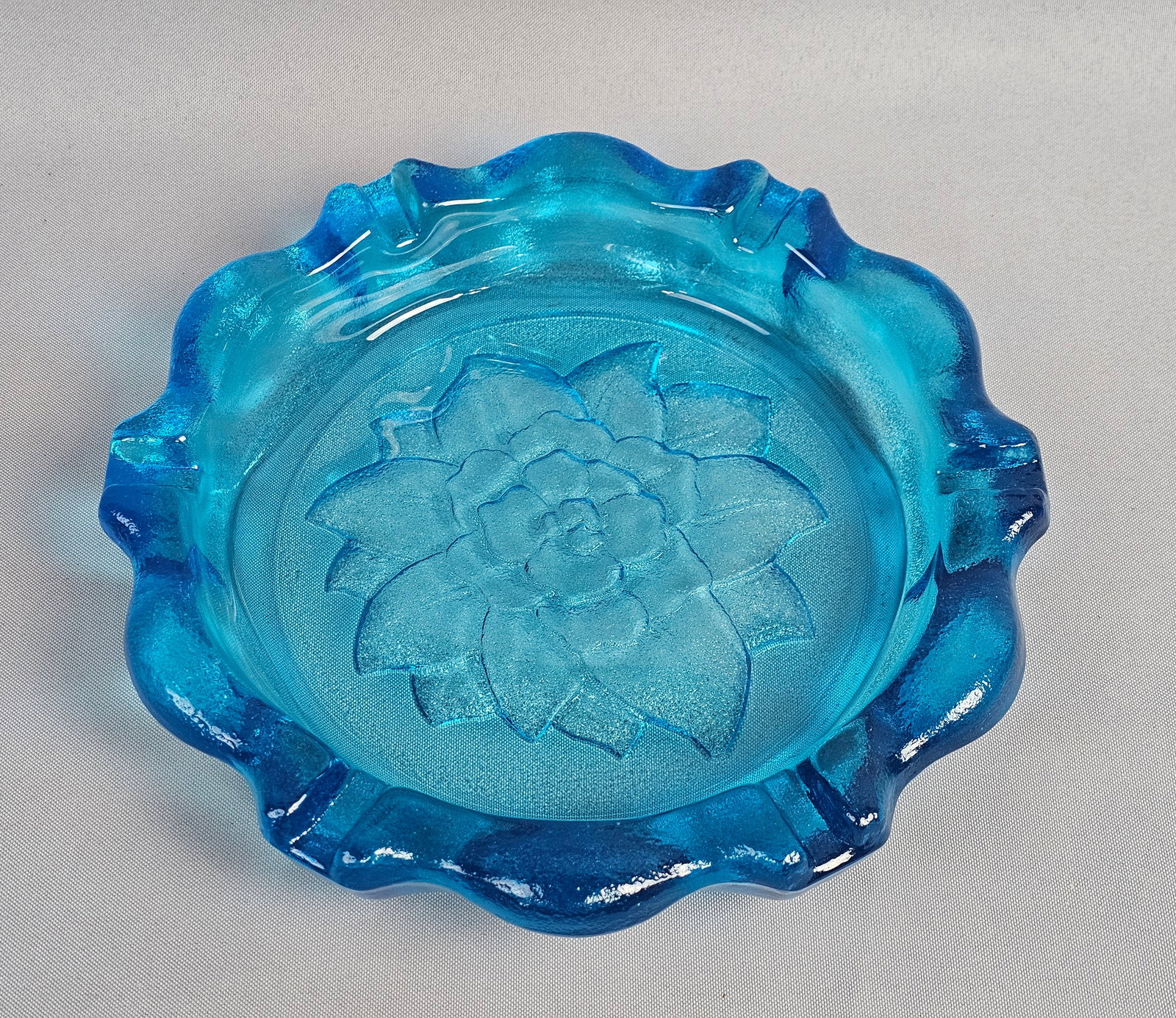 Large Blue Pressed Glass Ashtray Attributed to Indiana Glass: This large pressed glass ashtray is attributed to the Indiana Glass Company as part of the Tiara Exclusives line. Diameter: Approximately 9 inches. The item is in good vintage condition with light sur