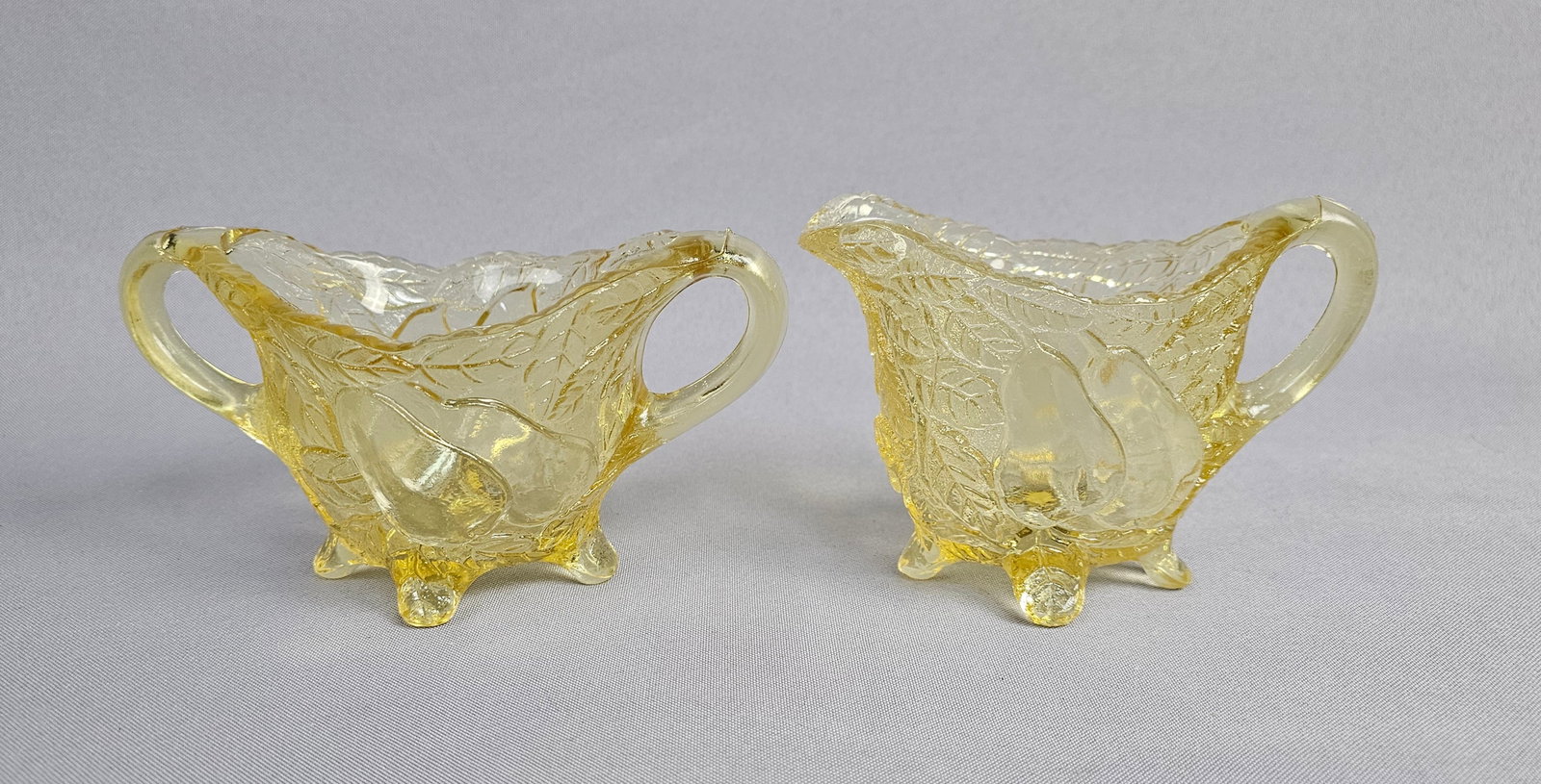 Tiara Exclusives Yellow Pressed Glass Pear Pattern Creamer and Sugar Bowl Set: A two-piece table set produced for Tiara Exclusives in transparent yellow pressed glass. The set consists of one creamer with a single handle and pouring spout and one open sugar bowl with dual handle