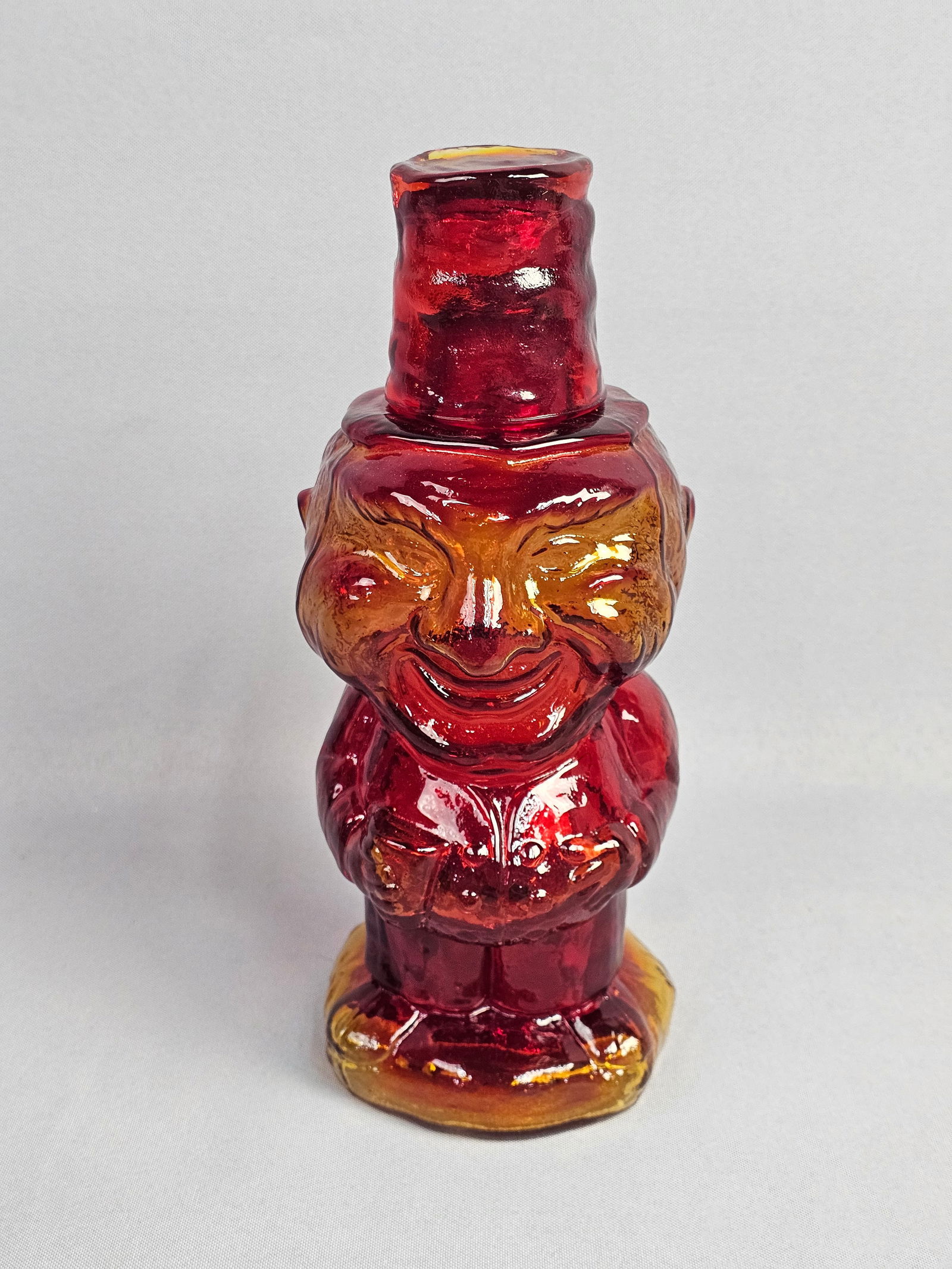 Vintage Amberina Glass Three Wise Monkeys Figural Bottle: A figural glass bottle depicting the Three Wise Monkeys, representing the motifs of See No Evil, Hear No Evil, and Speak No Evil, arranged in a vertical stack. The object is crafted from Amberina glas