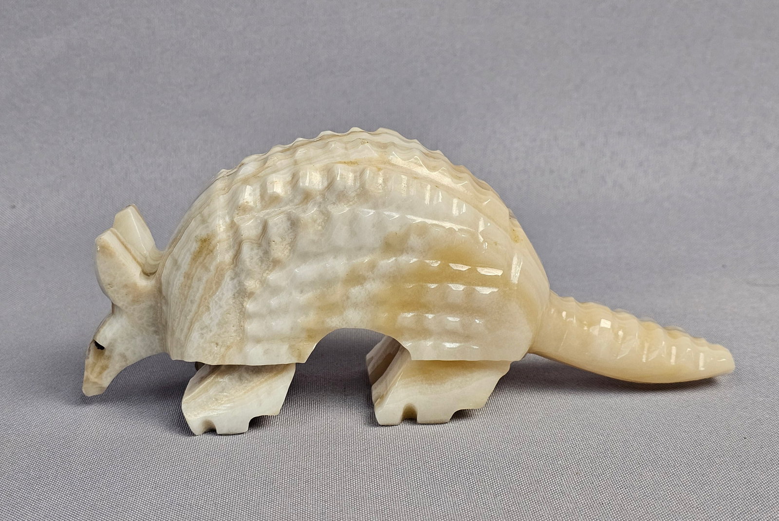 Southwestern Style Carved Banded Onyx Armadillo Figurine: This hand-carved figurine represents an armadillo, executed in a style consistent with Southwestern United States and Mexican folk art, often categorized as a fetish carving. The item is carved from