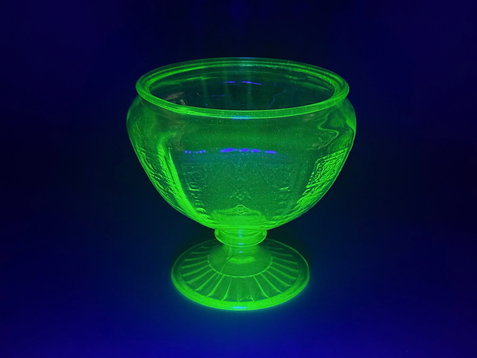Hocking Glass Company Princess Pattern Green Uranium Glass Jar: The piece is composed of machine-pressed green uranium glass, also known as Vaseline glass, that displays a strong green fluorescence under ultraviolet light. The exterior is decorated with rectangula