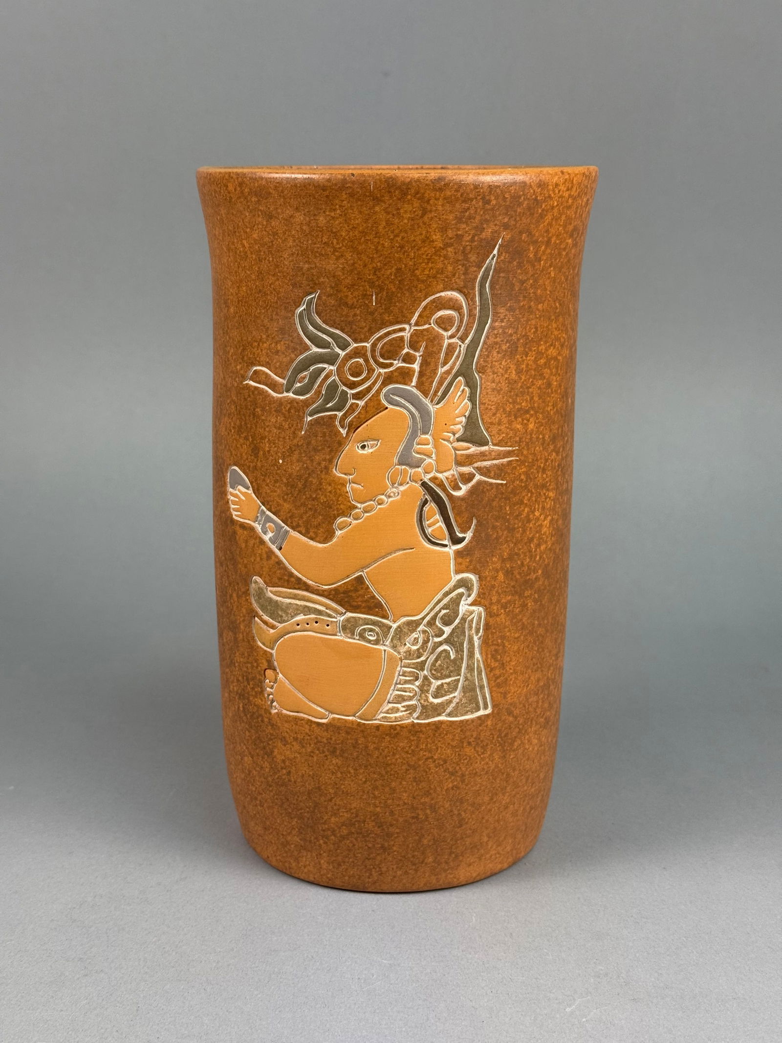 Mexican Folk Art Terracotta Vase with Maya Style Figurative Decoration: This tall cylindrical vessel is constructed of terracotta earthenware with a slightly flared rim and a gently tapered body. The exterior surface is finished with a mottled brown and orange slip. \This