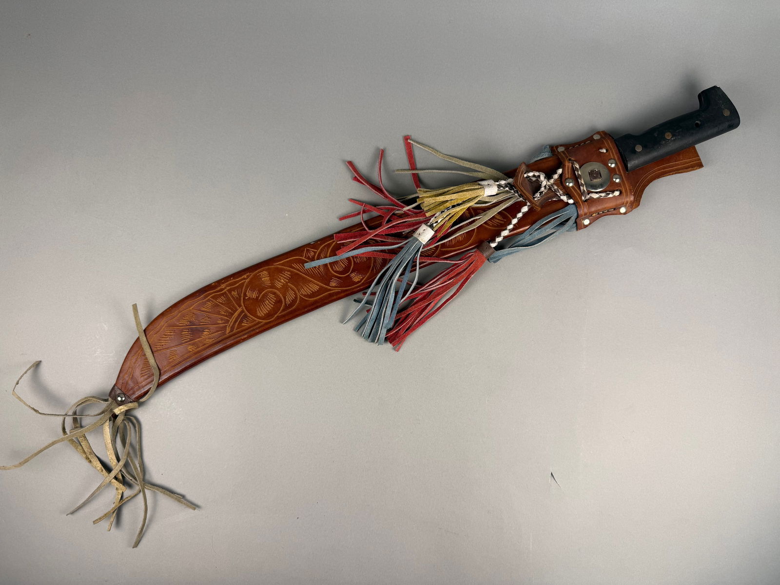 Collins and Co. Legitimus Machete with Ornate Tooled Leather Scabbard: This lot features a mid-to-late 20th-century machete manufactured by Herramientas Collins S.A. in Guatemala under license from Collins and Co. of Hartford, Connecticut. The tool is constructed with a