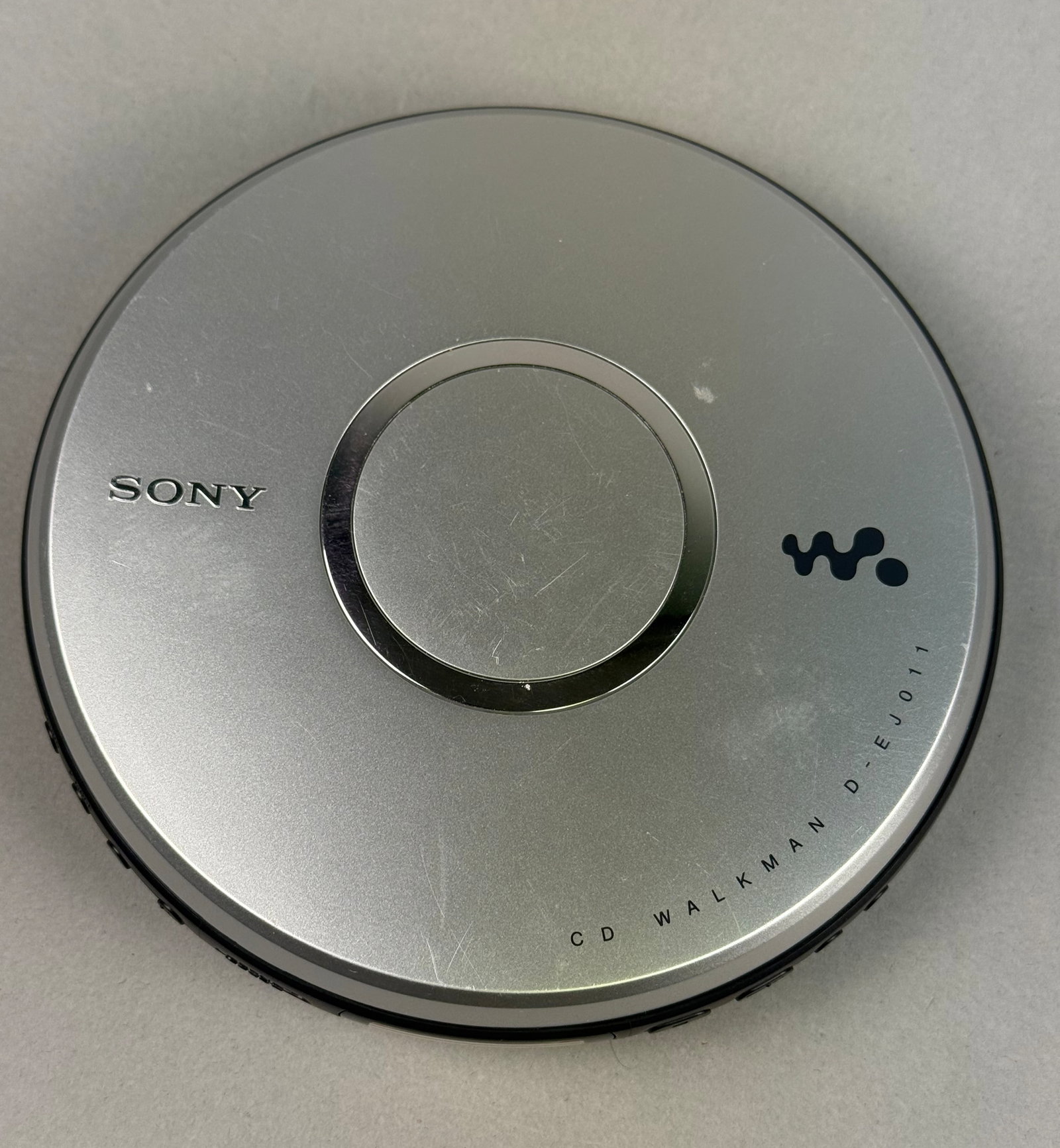 Sony CD Walkman Portable CD Player Model D-EJ011: Tested and working. This Sony CD Walkman, model D-EJ011, is a portable compact disc player constructed with a silver-tone plastic top and a black plastic lower housing. The top lid features the Sony b