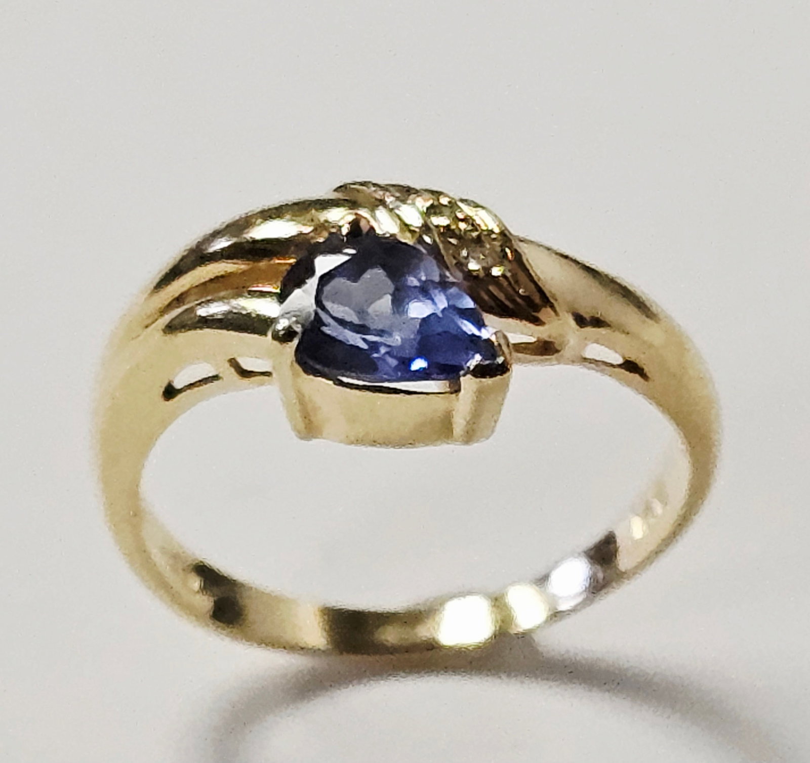 14K Gold Pear Cut Tanzanite Ring 3.0 Grams: A 14 karat yellow gold fashion ring featuring a bypass-style shank. The design centers on a single pear-cut blue gemstone held in a partial bezel setting. The interior of the band is marked with a 14K