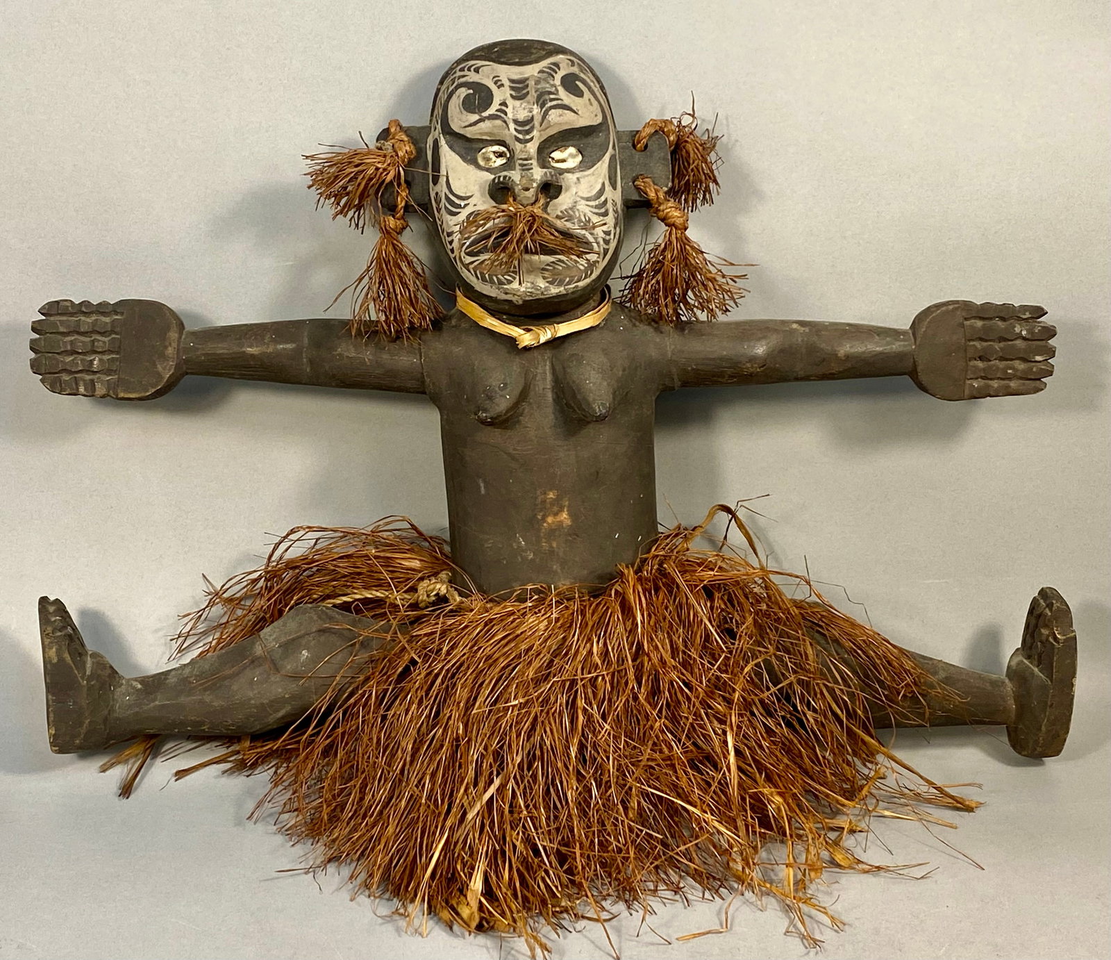 Melanesian Style Carved Wooden Anthropomorphic Female Figure with Mixed Media: This hand-carved wooden anthropomorphic figure is attributed to the Melanesian region, displaying stylistic characteristics common to Papua New Guinea. The figure is depicted as a female in a seated, 
