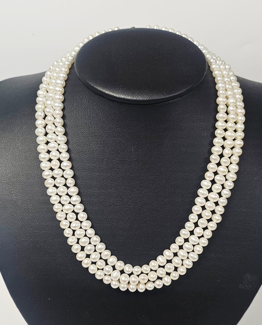 Triple-Strand Cultured Pearl Necklace 14K Gold Clasp: A triple-strand necklace featuring white cultured pearls. The pearls are slightly sub-baroque in shape and are individually knotted on silk thread. The necklace is secured with an ornate rectangular f