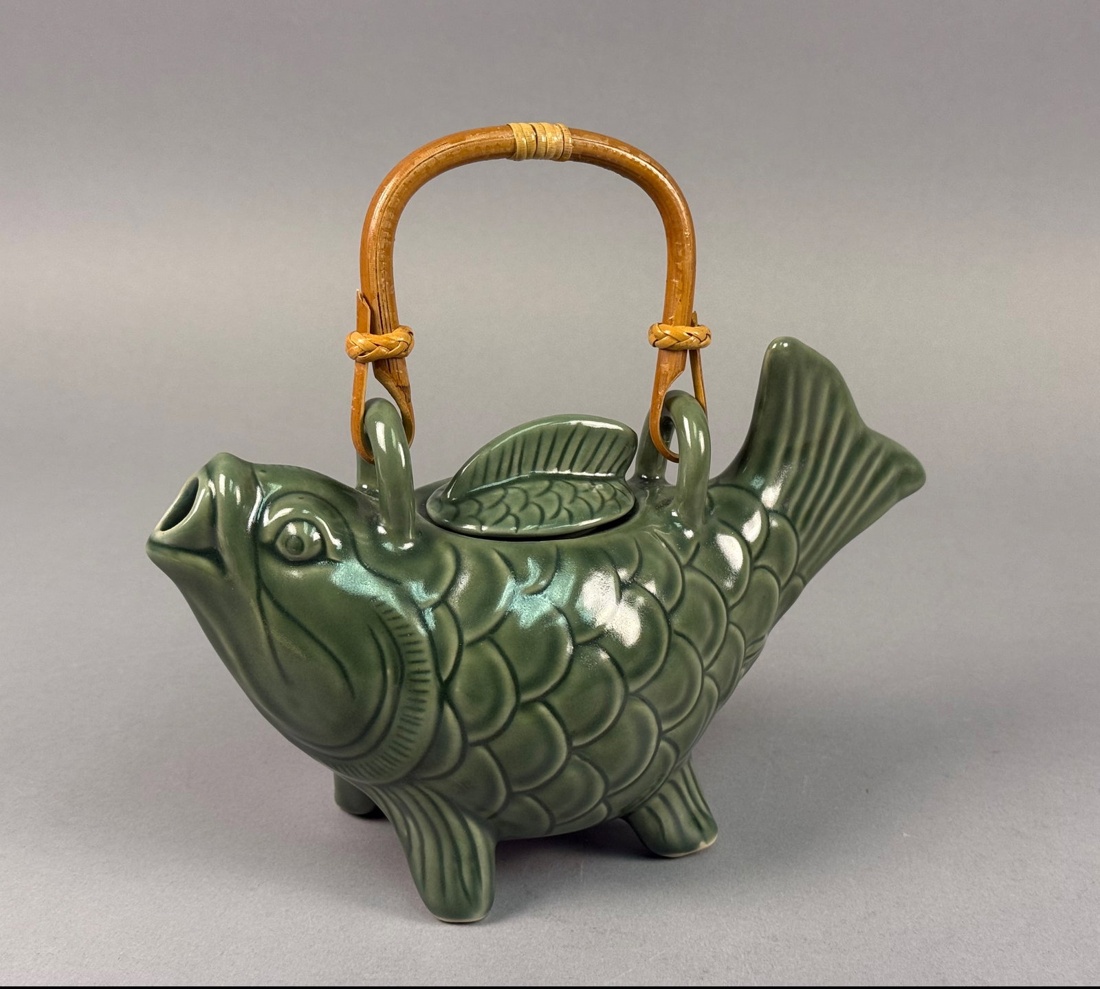 Novica Collection Indonesia Green Glazed Ceramic Fish Teapot: A contemporary figural teapot from the Novica Collection, produced in Indonesia. The piece is modeled in the form of a fish, with the open mouth serving as the spout and the body resting on four fin-s