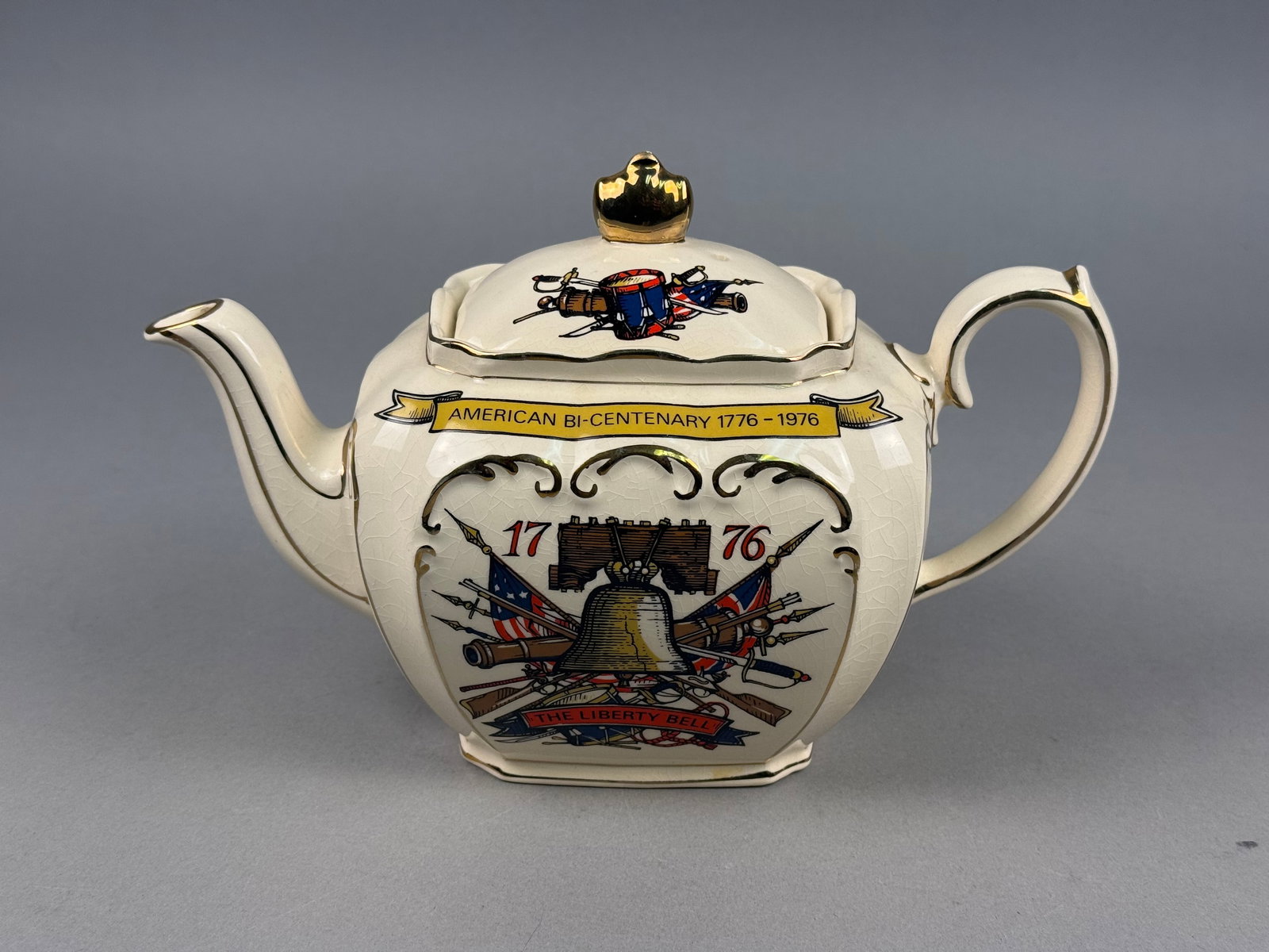James Sadler American Bicentennial Commemorative Earthenware Teapot: This glazed earthenware teapot was produced by James Sadler and Sons Ltd. to commemorate the 1976 American Bicentennial. The vessel features a bulbous, slightly faceted body with a curved spout and a