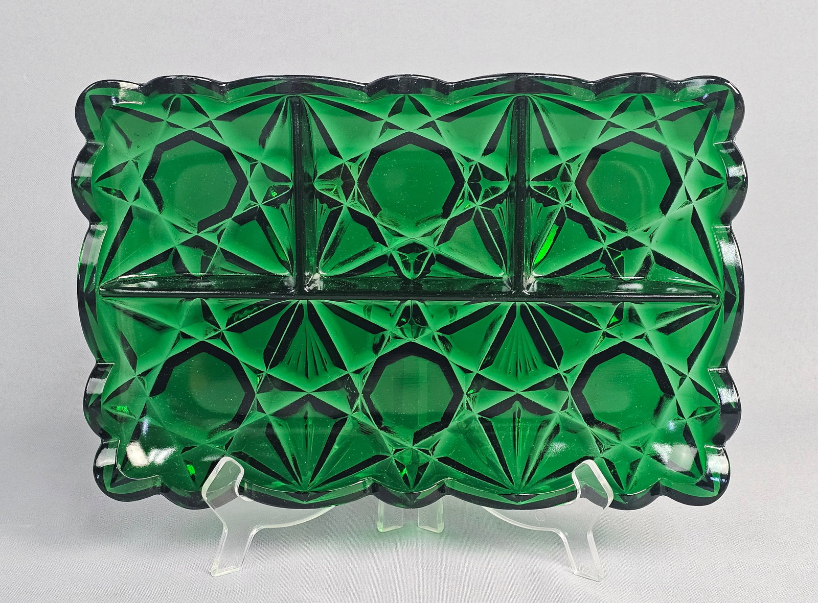 Tiara Indiana Glass Emerald Green Pressed Glass Divided Serving Tray: A rectangular divided relish or serving tray in deep emerald green pressed glass. The exterior features a complex Art Deco geometric pattern consisting of radiating starbursts alternating with large,