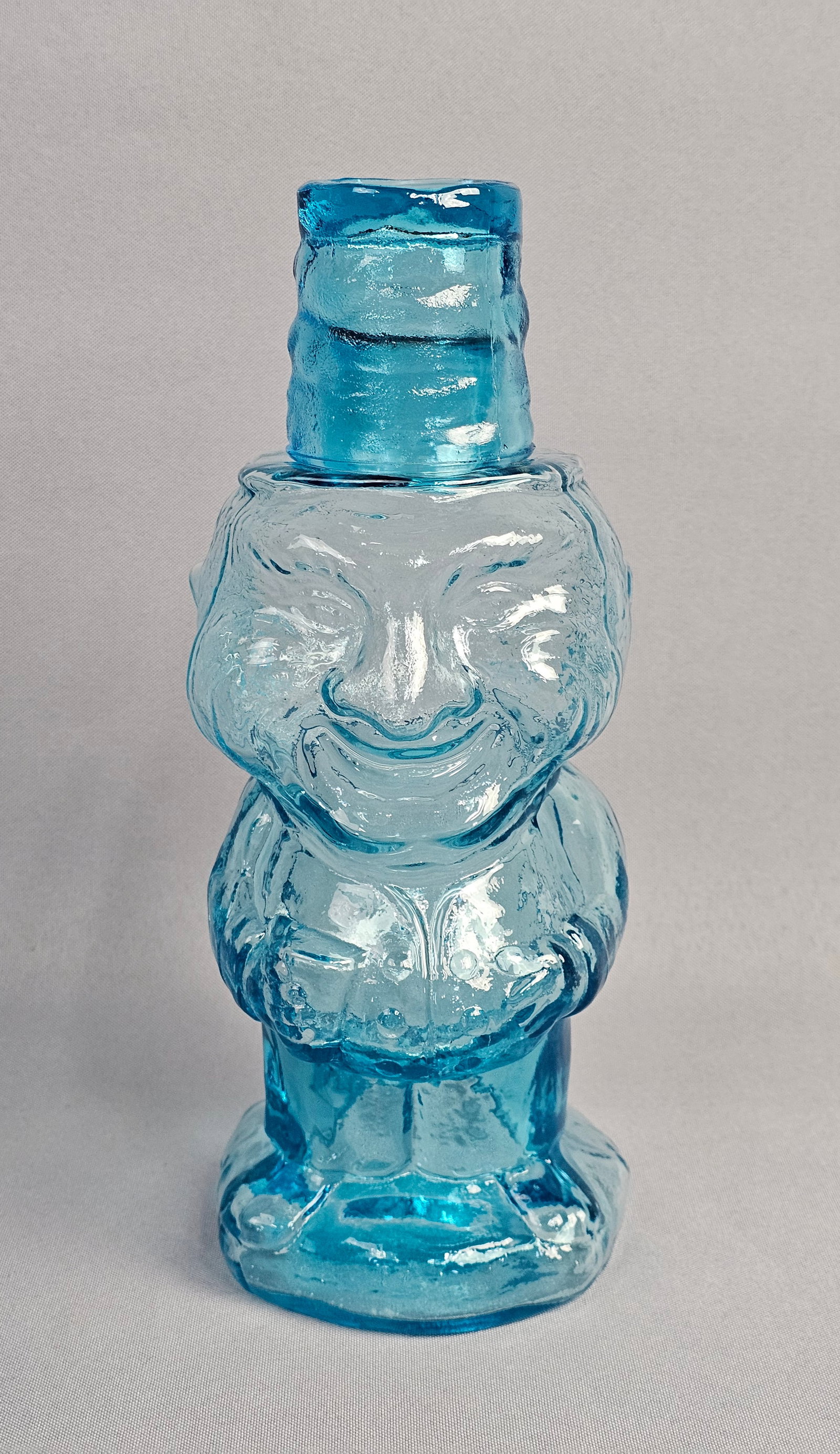 Indiana Glass Tiara Jolly Mountaineer Blue Glass Decanter: This figural decanter is produced in the Jolly Mountaineer pattern by Indiana Glass for Tiara Exclusives. The item is constructed from transparent light blue pressed glass. Height: 10 inches 