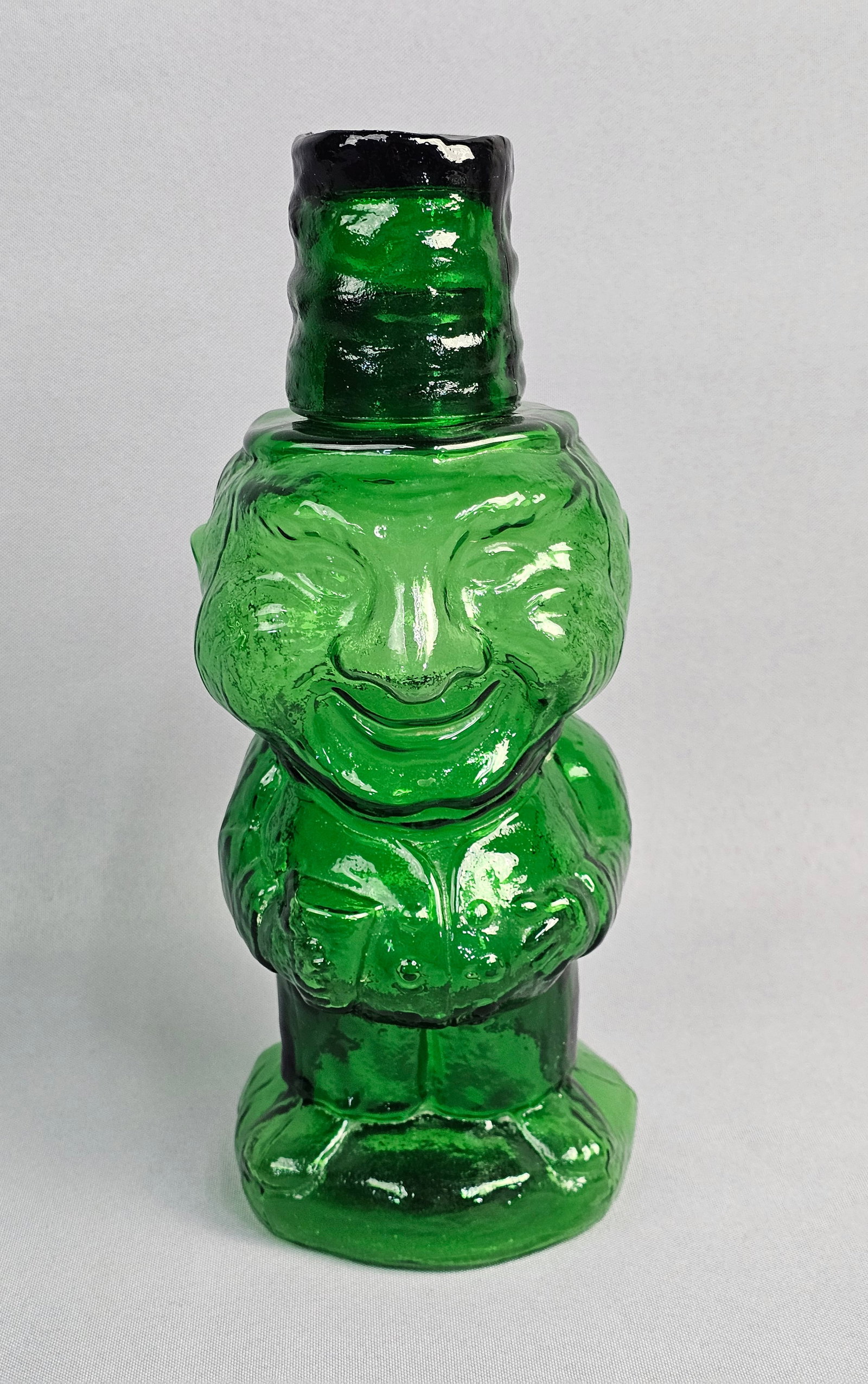 Indiana Glass Tiara Jolly Mountaineer Green Glass Figural Decanter: This figural glass decanter is identified as the Jolly Mountaineer pattern, manufactured by Indiana Glass for Tiara Exclusives. The piece is made of emerald green translucent pressed glass. 