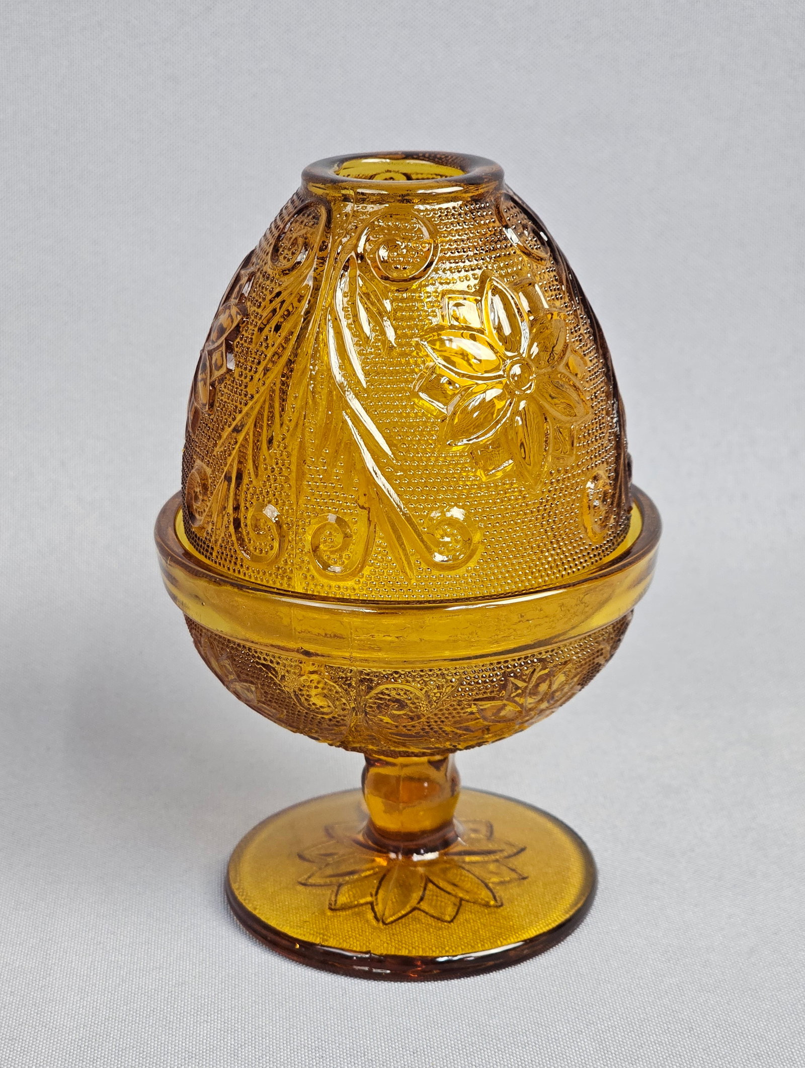 Tiara Exclusives Amber Sandwich Pattern Fairy Lamp: A two-piece pressed glass fairy lamp in the Sandwich pattern, marketed by Tiara Exclusives and produced by the Indiana Glass Company. The item is constructed of amber-colored glass and consists of an