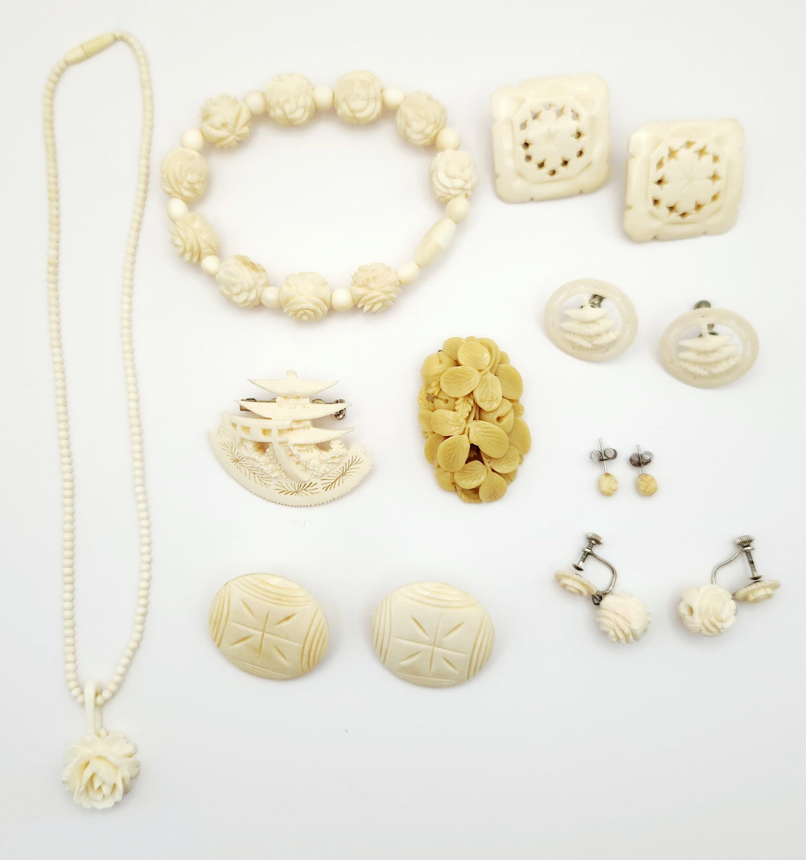 Assortment of Vintage Carved Celluloid & Bone Jewelry: This collection consists of vintage jewelry items fashioned from carved cream-colored organic and synthetic materials, including bone and celluloid. The group includes a beaded necklace with a floral
