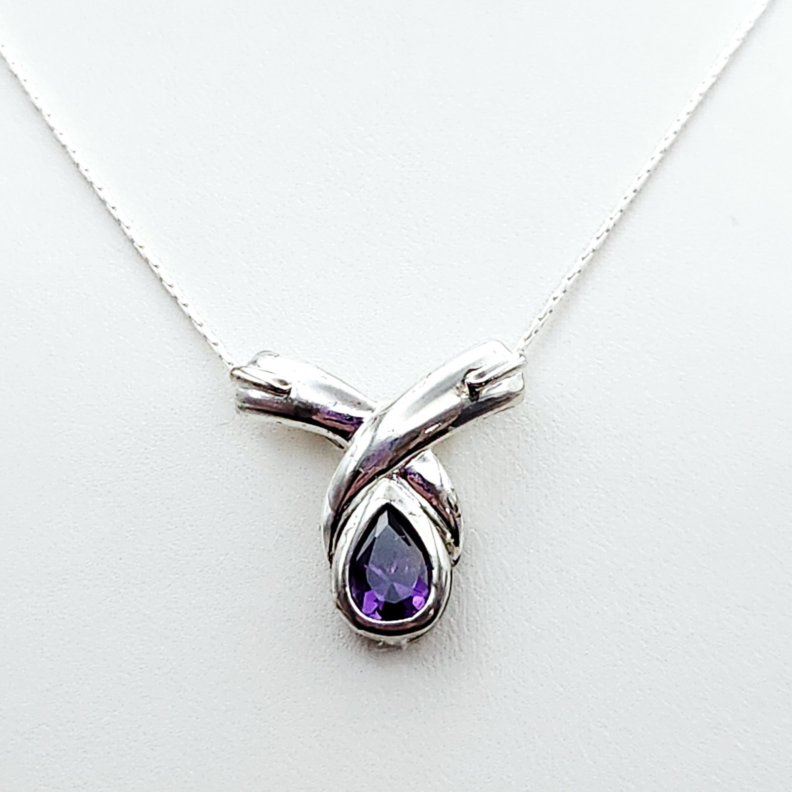 Sterling Amethyst Necklace 7.6 Grams: A sterling silver necklace featuring a 24 inch chain marked ITALY 925 and a pendant with an amethyst pear shaped gemstone measuring approximately 1 inch. Necklace is 24". Weighs 7.6 Grams. Overa
