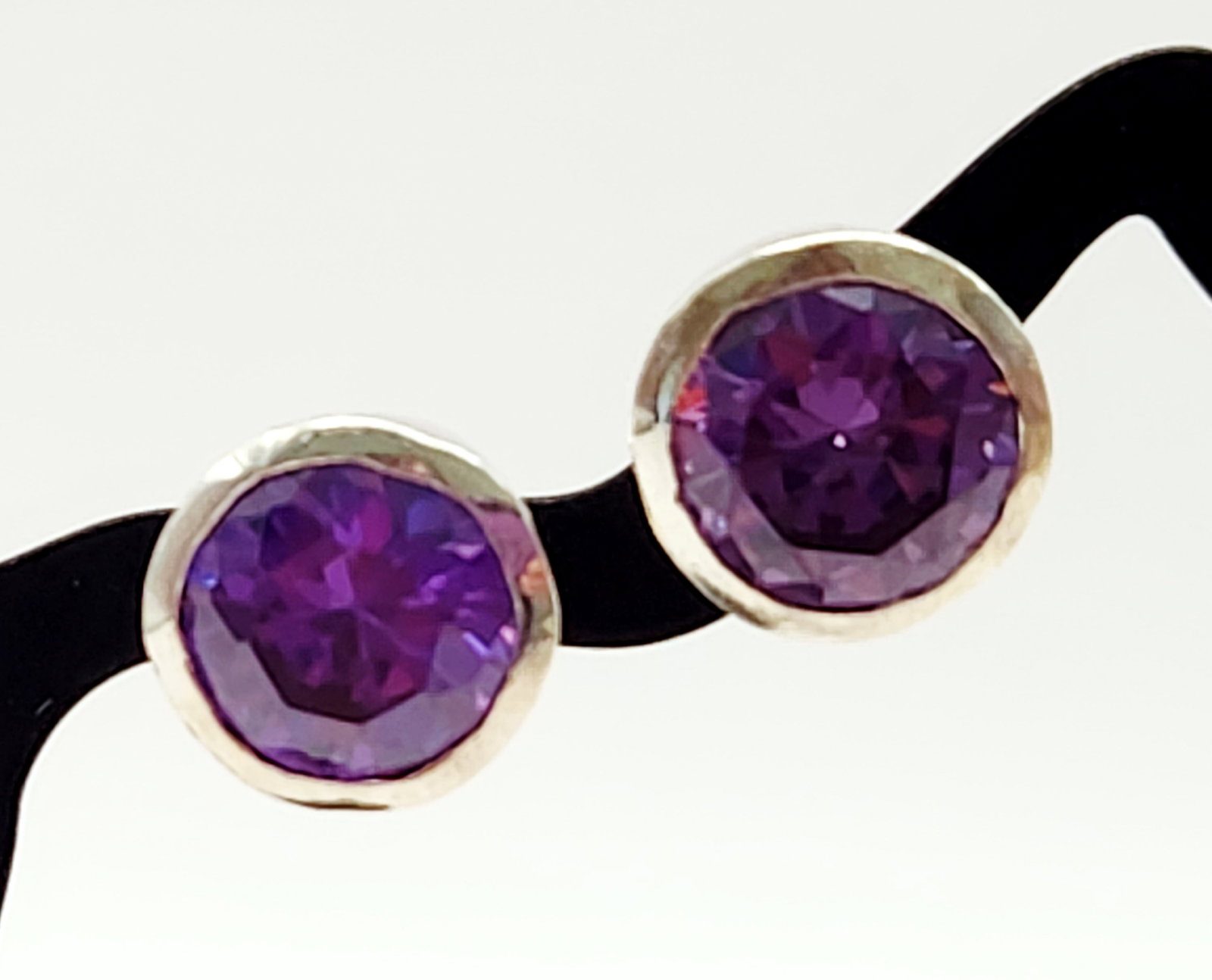 Sterling Amethyst Earrings 4.2 Grams: A pair of amethyst stud earrings set in 925 sterling silver bezel mounts, weighing approximately 4.2 grams and measuring about 3/8 inch in diameter. Overall very good condition.