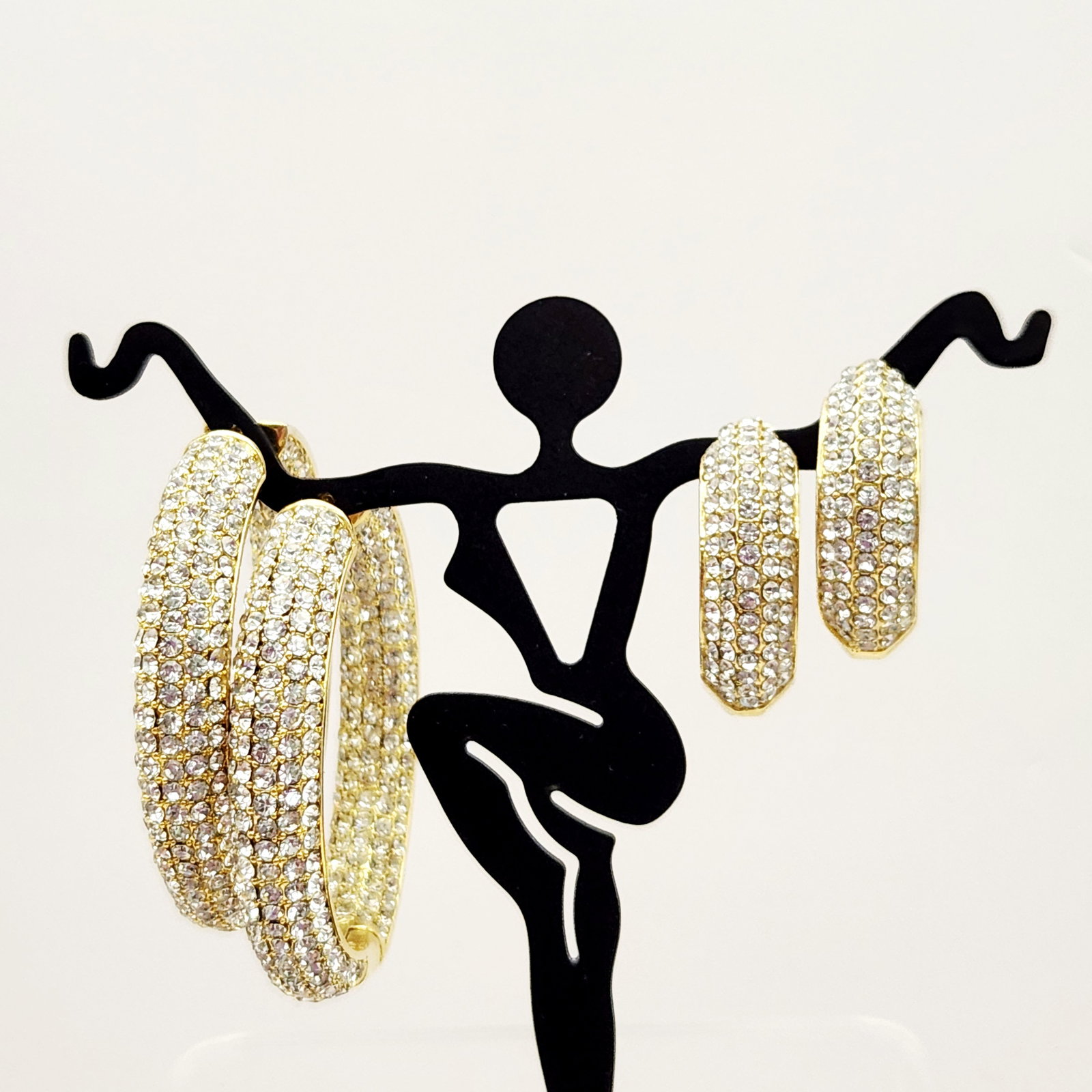 Gold Toned Stone Set Hoop Earrings: Two pairs of gold-toned hoop earrings featuring multiple rows of clear colorless stones, with the larger pair measuring approximately 1.5 inches in diameter and the smaller pair marked PB CHINA measur