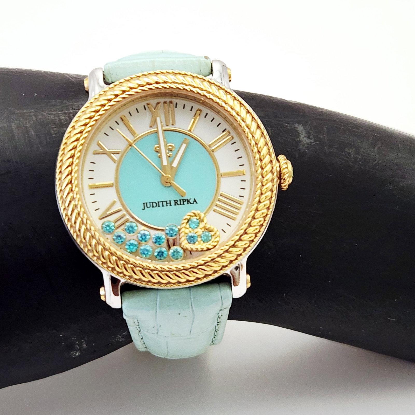 Judith Ripka Women's Two-Tone Floating Stone Wristwatch: A Judith Ripka women's wristwatch featuring a rope-textured bezel, floating blue stones on a light blue dial, and an embossed light blue leather strap measuring approximately 8.5 inches in length. Wa